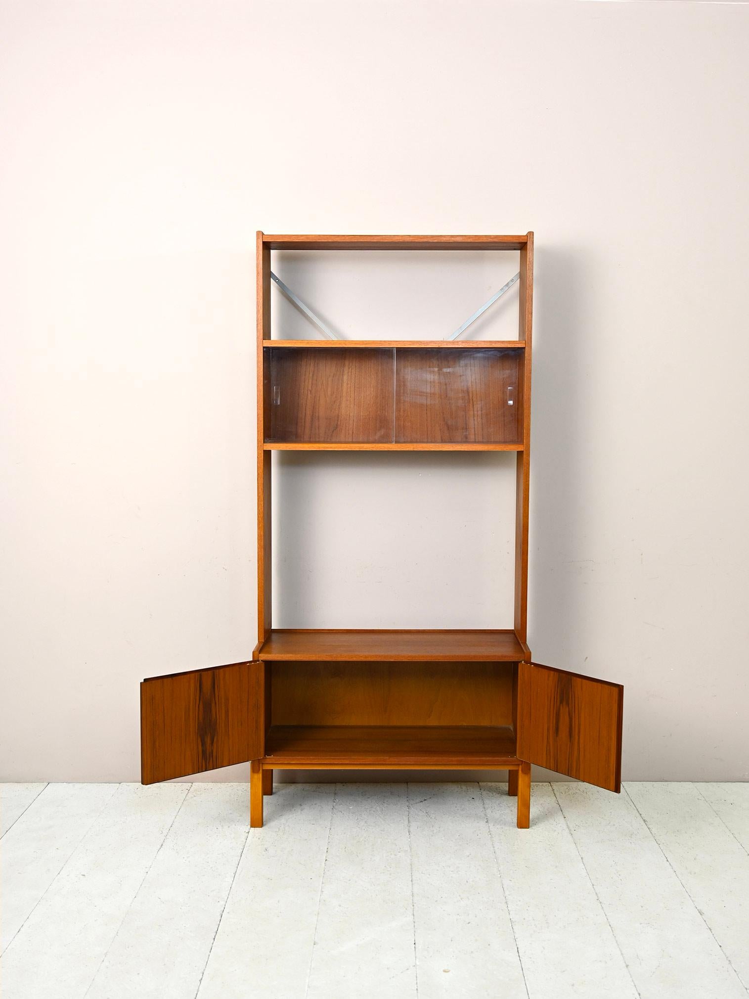 1960s storage cabinet with bookcase.

Original piece of Scandinavian modern antique furniture consisting of a low cabinet on which rests a frame with a shelf and a display cabinet.
The cabinet with storage space has two lockable hinged doors and can