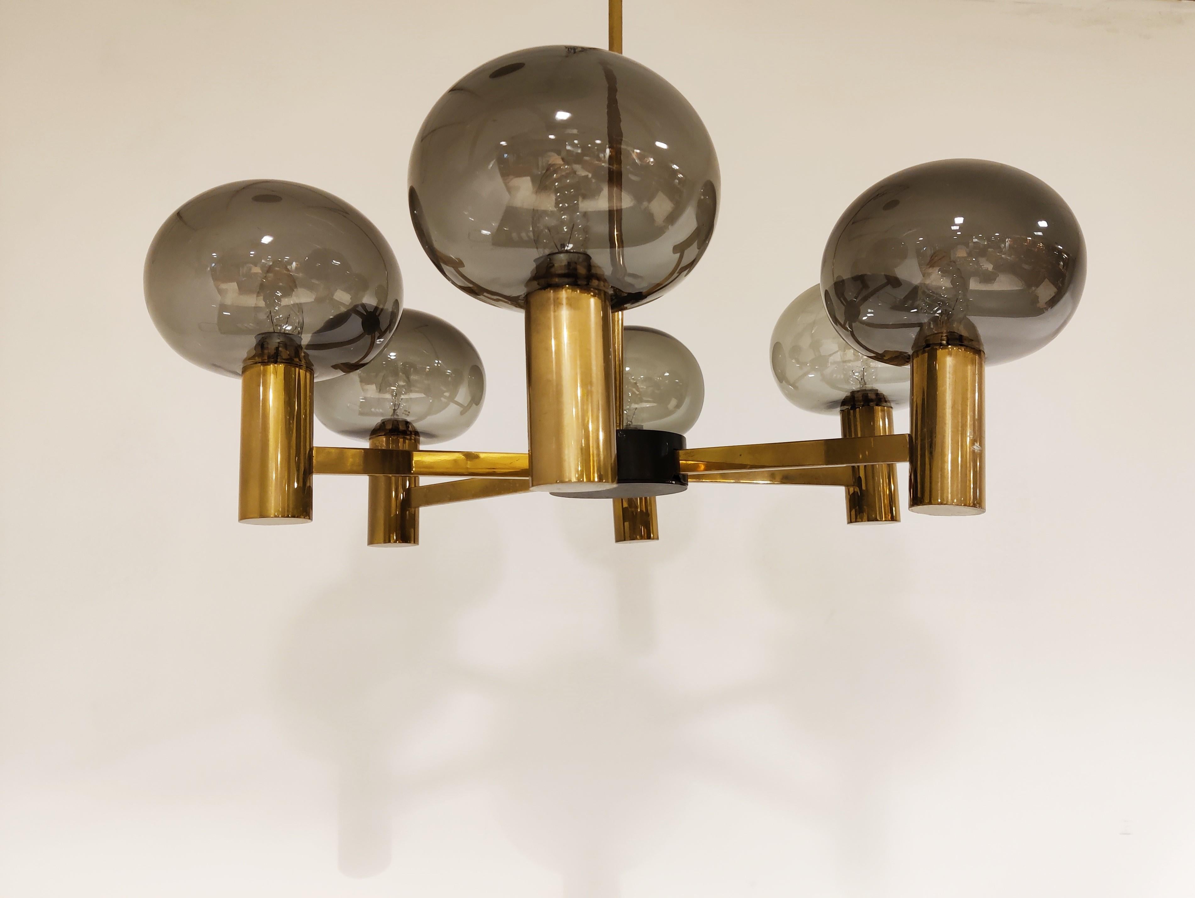 Beautiful mid century brass Swedish chandelier with smoked glass lamp shades.

The designed/manufacturer is unknown but it has a timeless design and emits a beautiful light.

Good original condition.

Tested and ready to use with regular E14