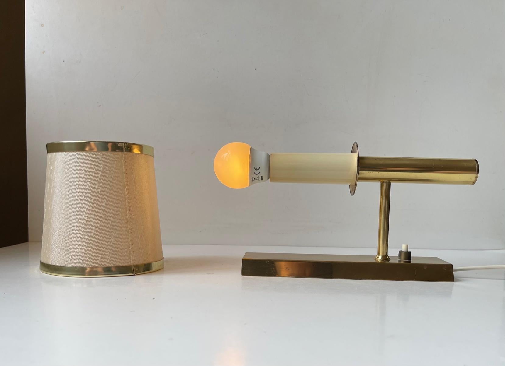 Fixed wall light designed and manufactured by Svend Mejlstrøm in Denmark during the 1960s or early 70s. Its made from polished brass and retains its pastel colored textile shade that came with it originally.
