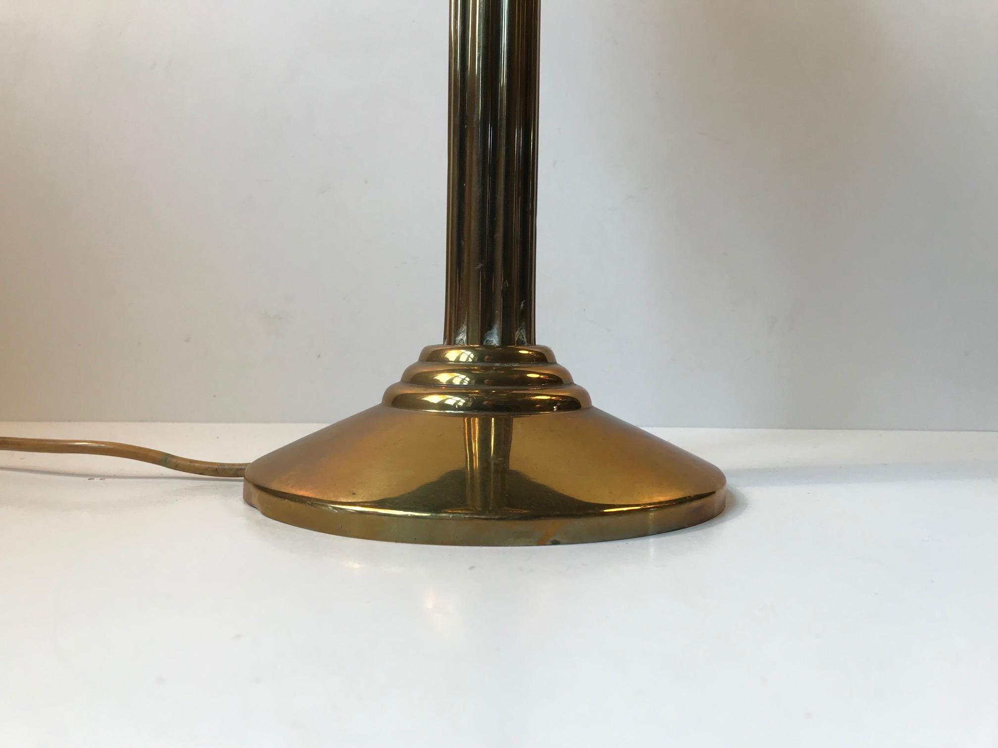 Unusual table light composed of brass and mounted with a spherical shade in marbled glass. Manufactured in Denmark during the 1970s or earlier a style deriving from the Art Deco movement. Please notice that the shade is loosely fitted to its brass