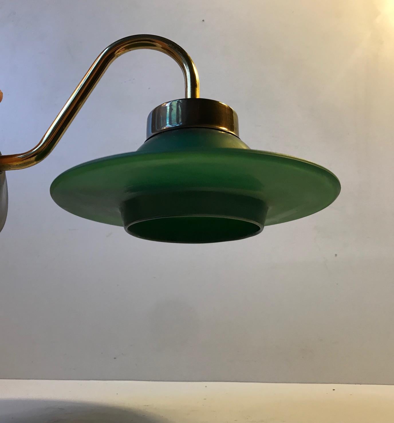 Up or downwards wall light made from solid brass. It has a Saturn / orbit shaped shade in green glass. Anonymous Scandinavian design/maker, circa 1960.