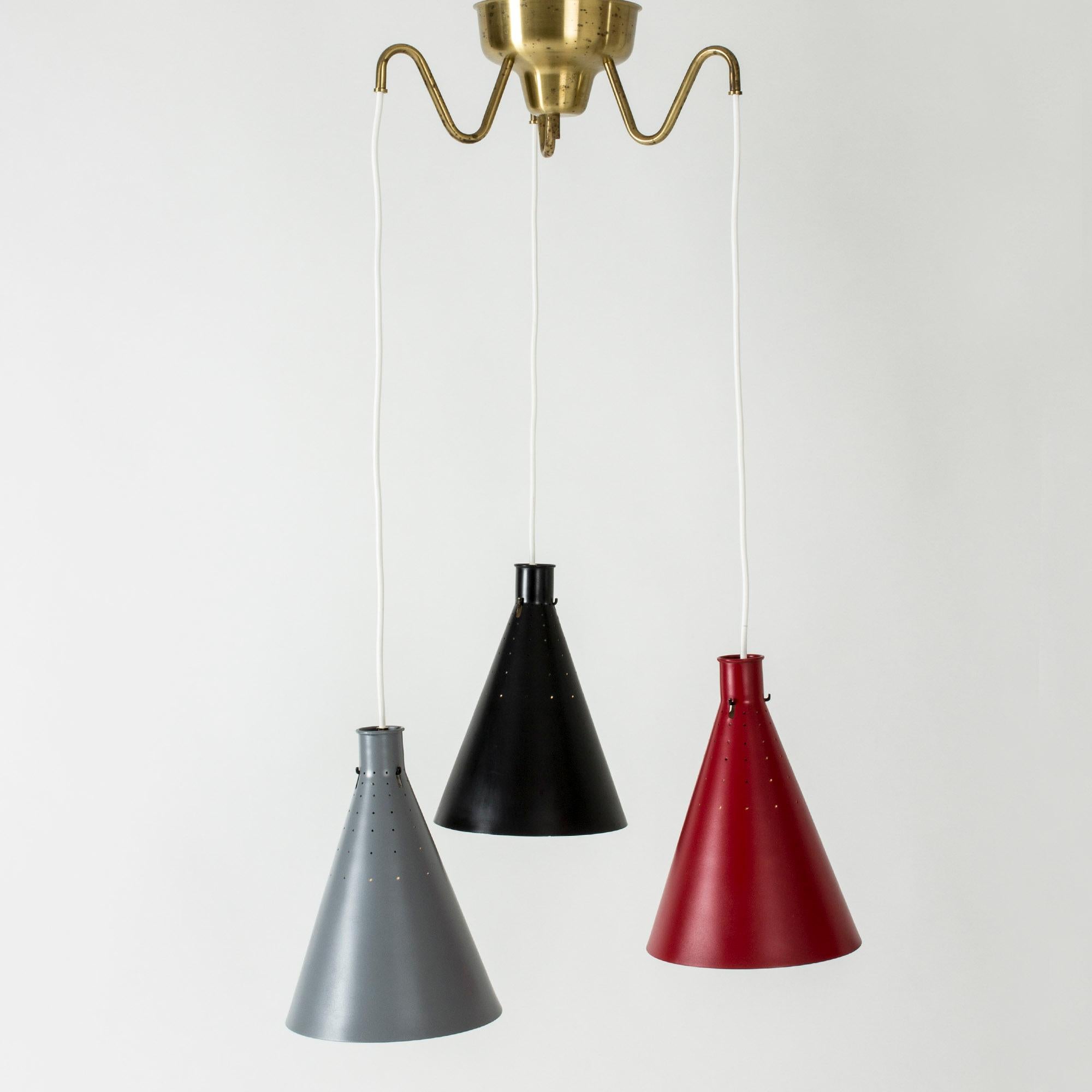 Elegant ceiling lamp with three lamp shades set at different heights, designed by Alf Svensson. Brass ceiling cup, metal shades lacquered red, grey and black. Shades perforated with small holes.