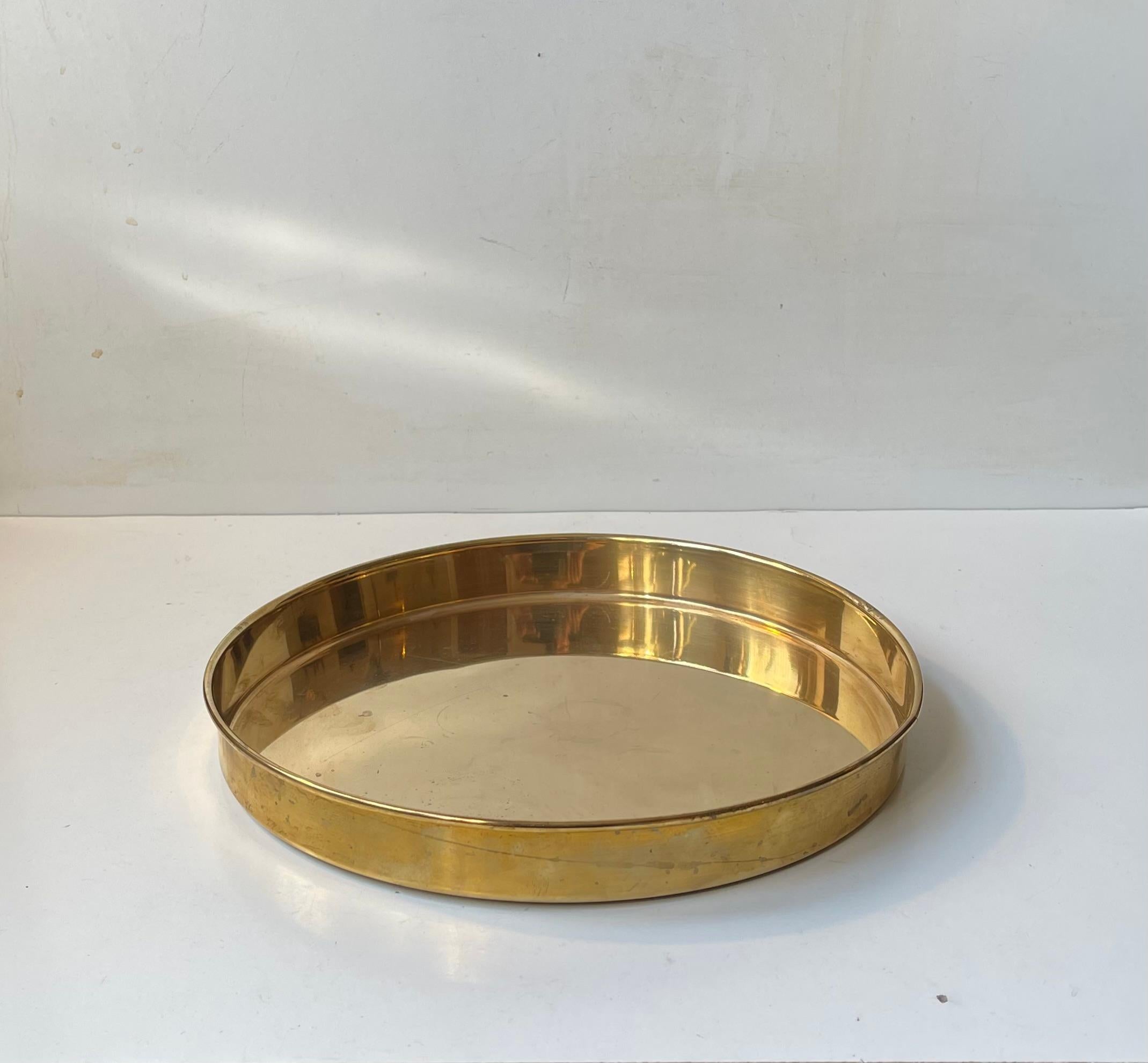 A stylish circular tray in solid brass. It was made during the 1960s or 1970s by Cawa in Denmark in a style reminiscent of Josef Frank and Stelton. It is suitable for serving drinks or as a 1-2 person breakfast tray. 
Measurements: D: 29 cm, H: 3.5