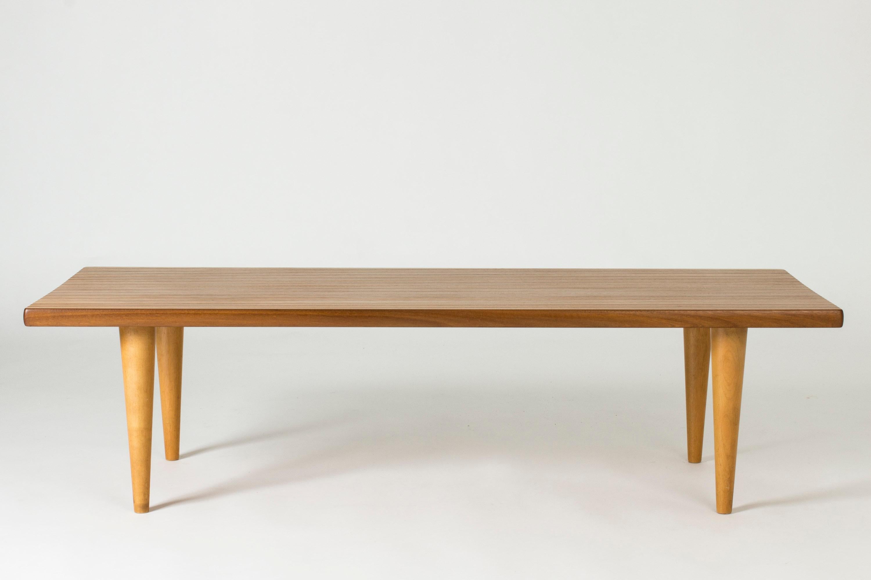 Étonnante table basse de Yngvar Sandström, au motif rayé créé par l'alternance de teck et de bouleau dans le plateau en bois massif. Un motif très cool sur les petits côtés.