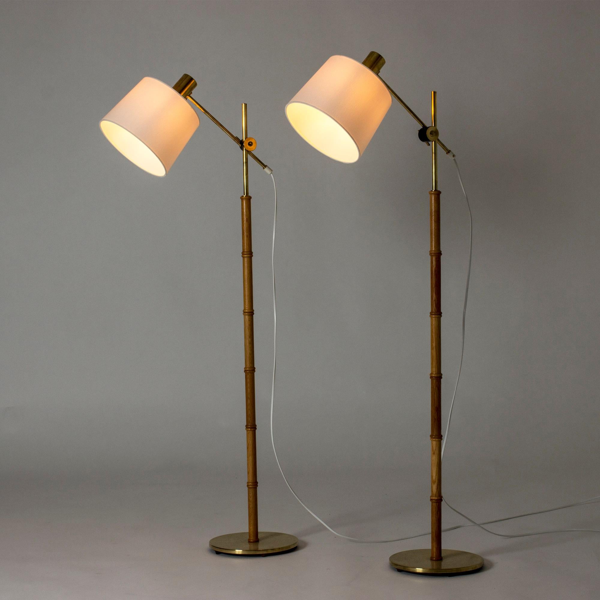 Pair of cool floor lamps from Falkenbergs Belysning, made from brass and oak sculpted in a bamboo stem design. Shades adjustable in height and angles.