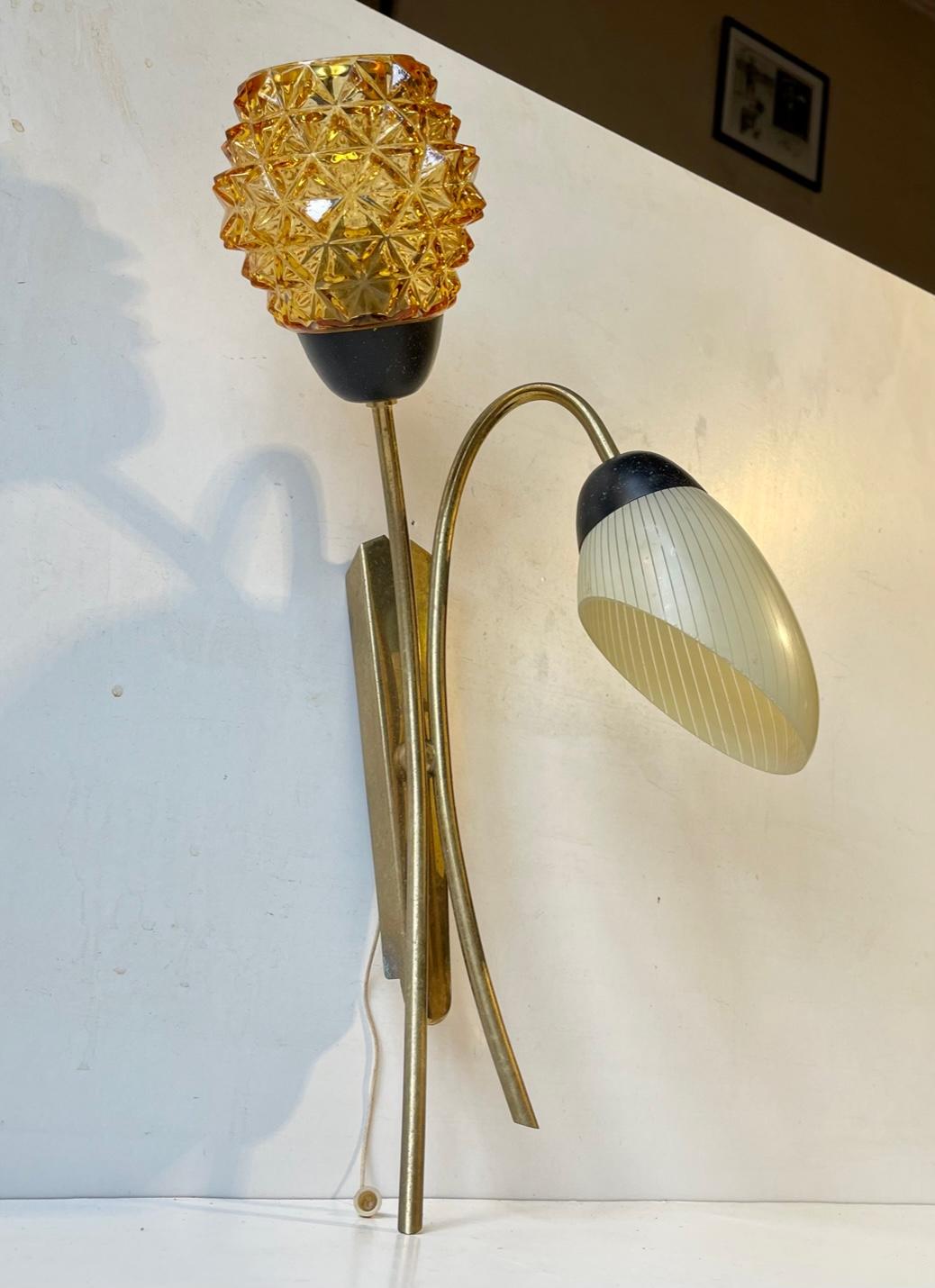Flower shaped double Sconce designed in a style reminiscent of Stilnovo and manufactured during the 1950s or 60s in Scandinavia. It is made from solid brass and each 'flower' shade is made from glass. One in pressed diamond pattern amber glass and