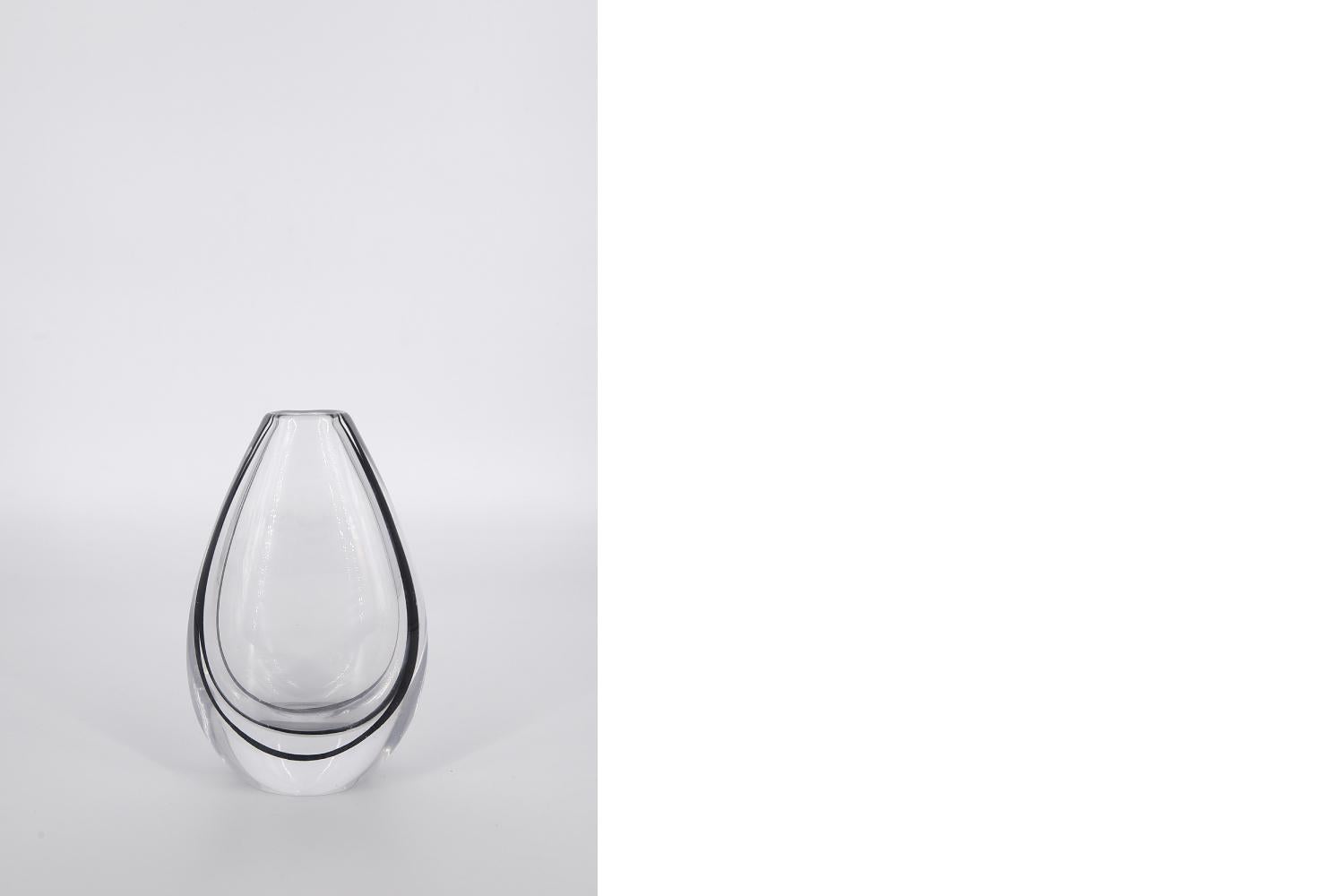 This glass vase from the Contour series was designed by Vicke Lindstrand for the Swedish glassworks Kosta Glasbruk during the 1950s. It is made of high quality clear crystal glass with a dark brown line inside the vase. The catalogue number us LH