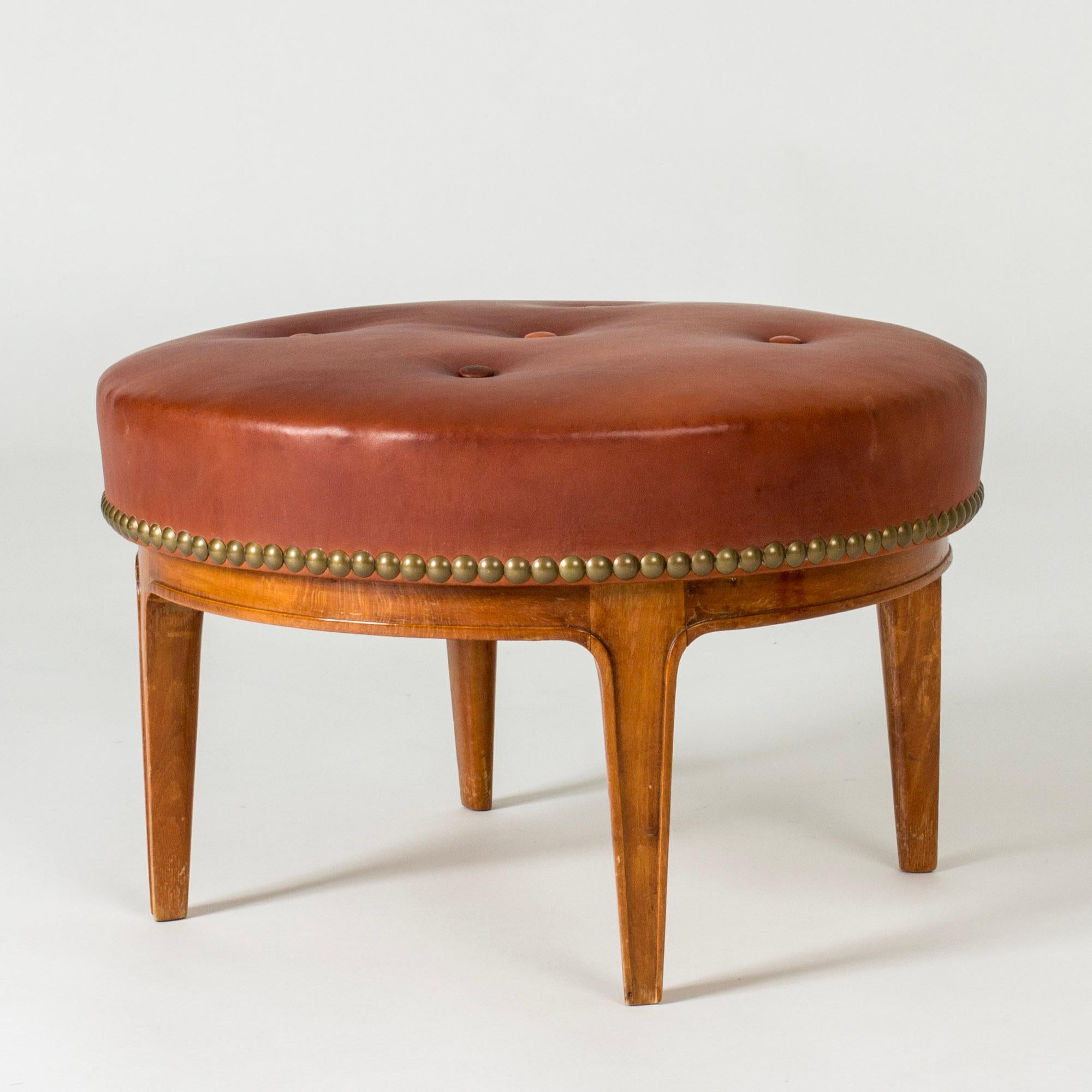 Lovely midcentury ottoman by Axel Larsson, with a mahogany base and dressed with elegant brown leather. Row of decorative brass nails around the edge.