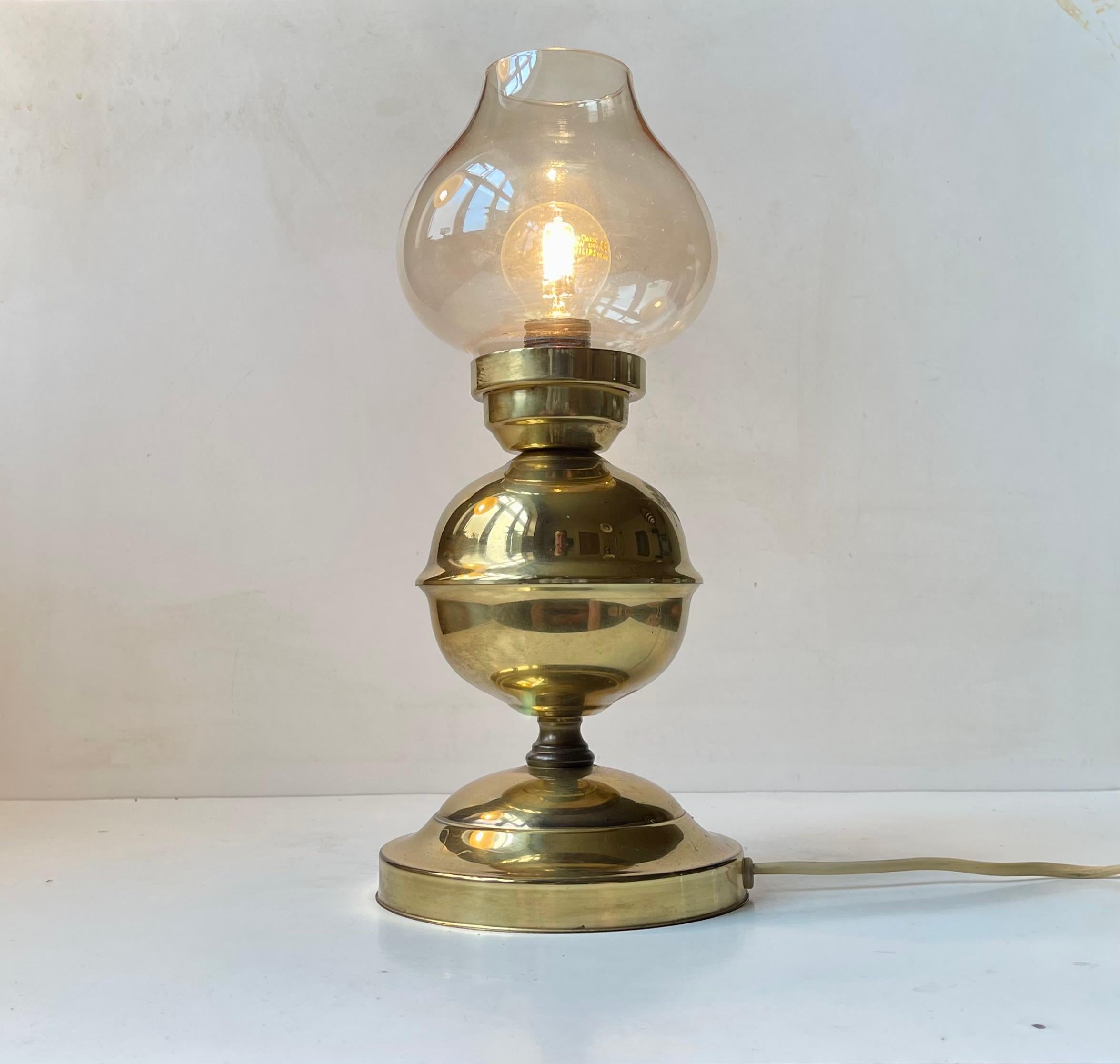 A nautical table lamp executed in solid brass and featuring a smoke glass shade.The on/off switch is at its cord. It was made by ABO in Denmark 1970-80 in a style reminiscent of Hans Agne Jakobsson. Measurements: H: 33 cm, D: 13/15