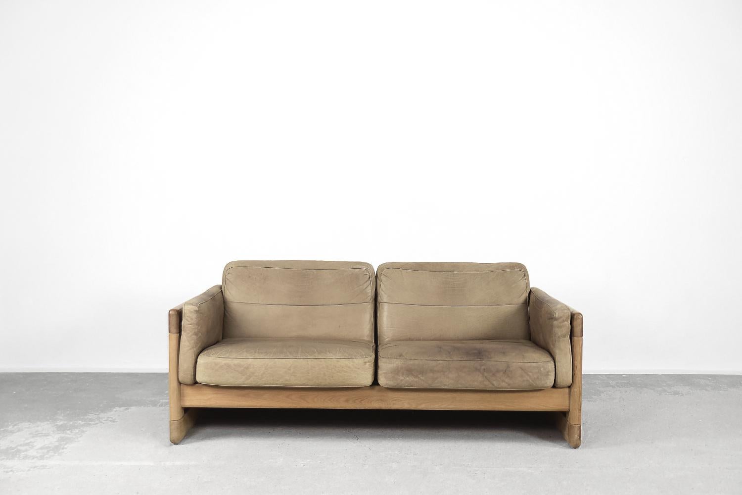 This two-seater sofa was produced in Scandinavia during the 1970s. The frame is made of solid oak wood with a natural color. The cushions are upholstered with natural leather in a shade of coffee brown. The sofa is equipped with side cushions. The