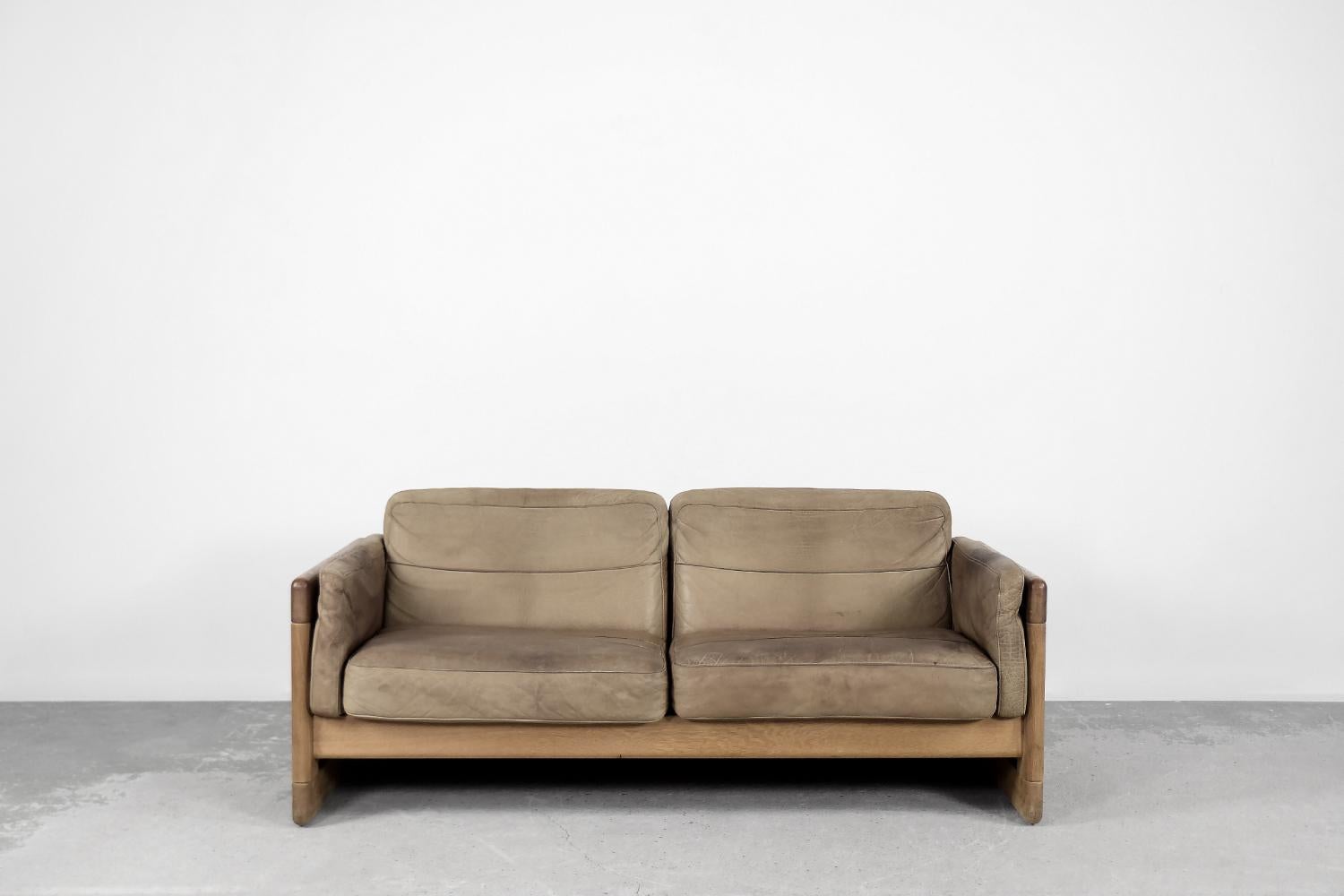 This two-seater sofa was produced in Scandinavia during the 1970s. The frame is made of solid oak wood with a natural color. The cushions are upholstered with natural leather in a shade of coffee brown. The sofa is equipped with side cushions. The