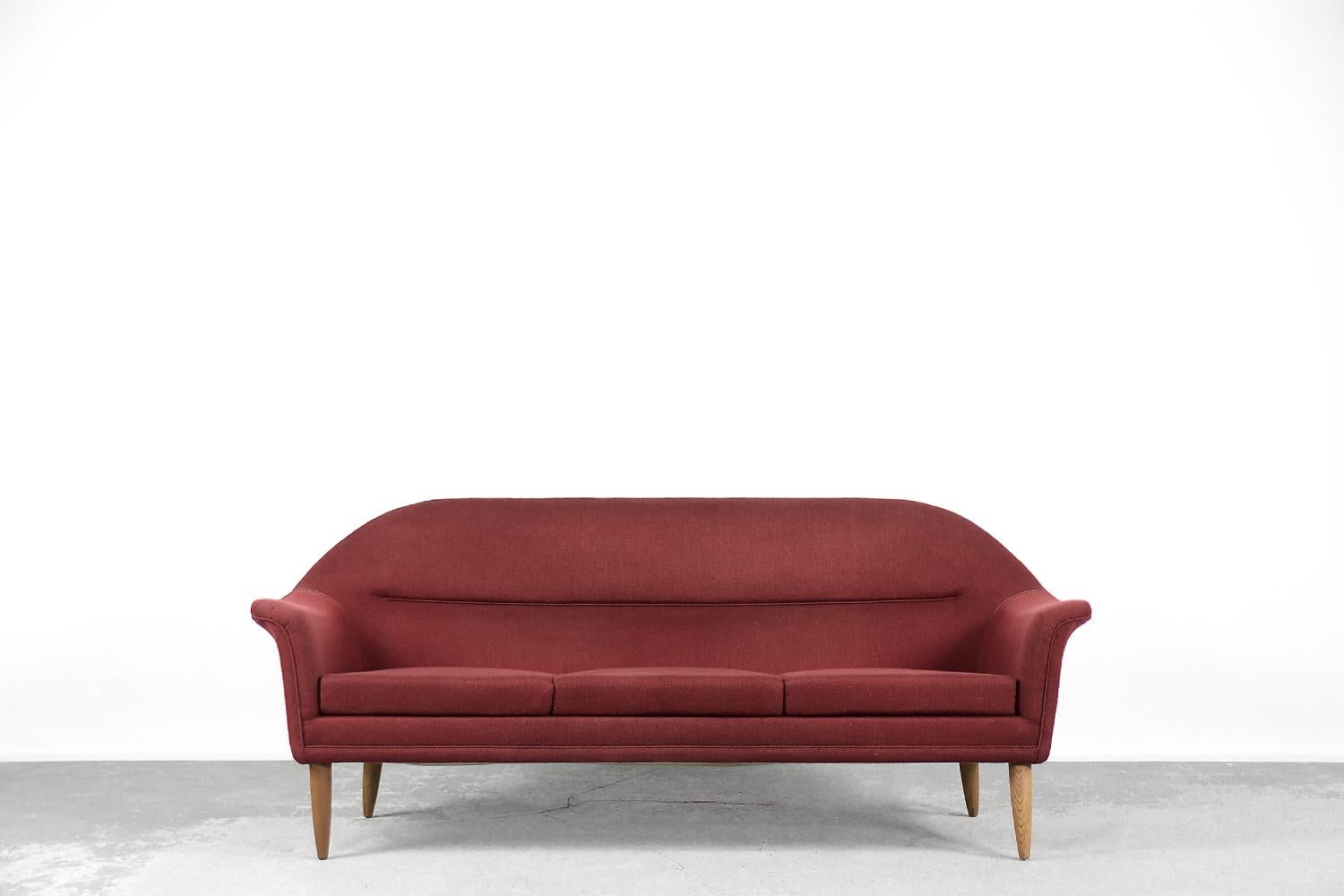 This three-seater sofa was made by the Swedish manufacturer Bröderna Anderssons during the 1950s. The sofa is upholstered with a high-quality material in a noble red color. It is an example of an old craft school, where the frame and armrests are