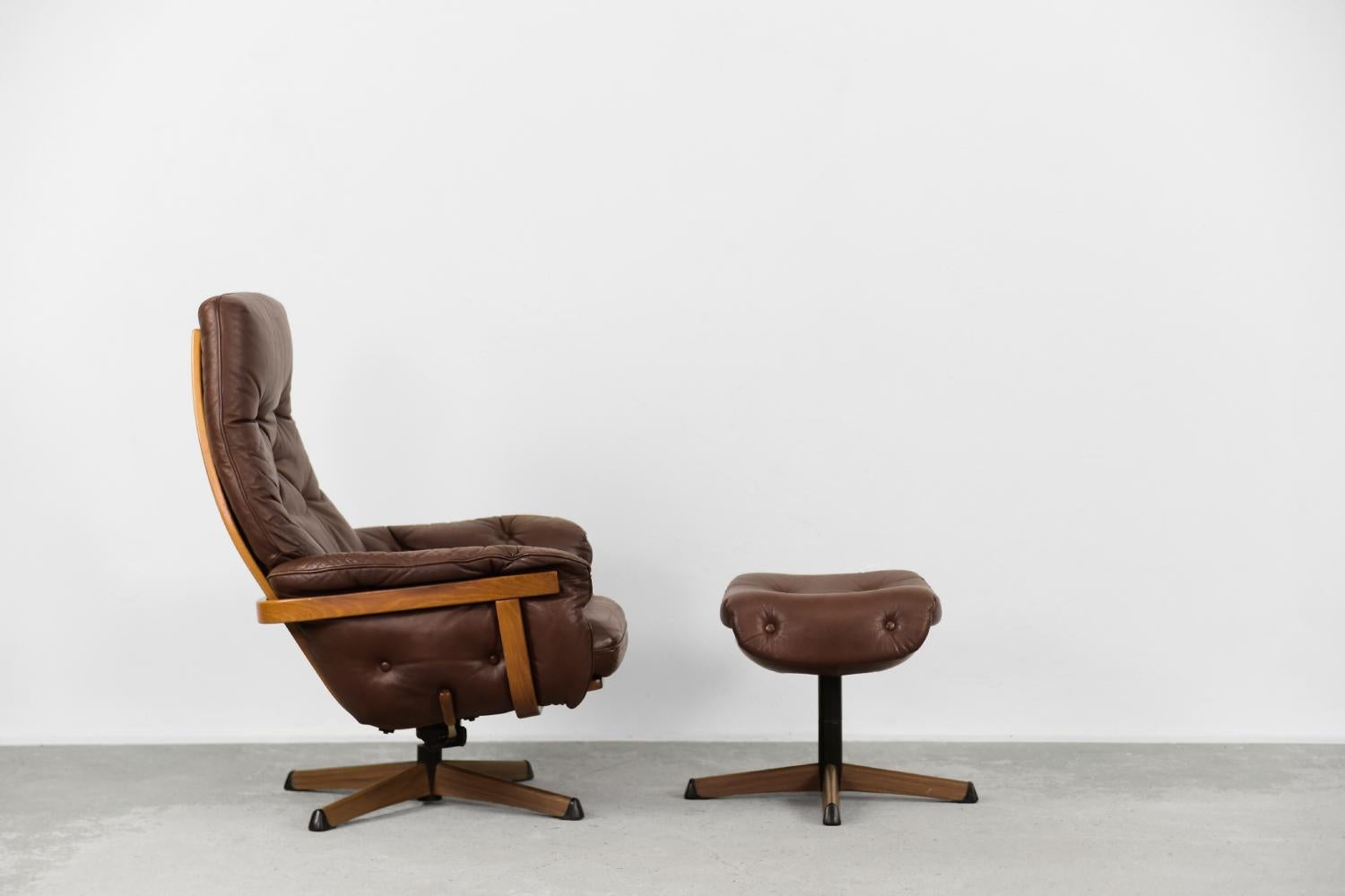 This modernist leather armchair and ottoman was produced by the Swedish Göte Möbler manufacture during the 1960s. The frame is made of solid wood and upholstered with brown natural leather with elegant quilting. The metal legs were covered with a