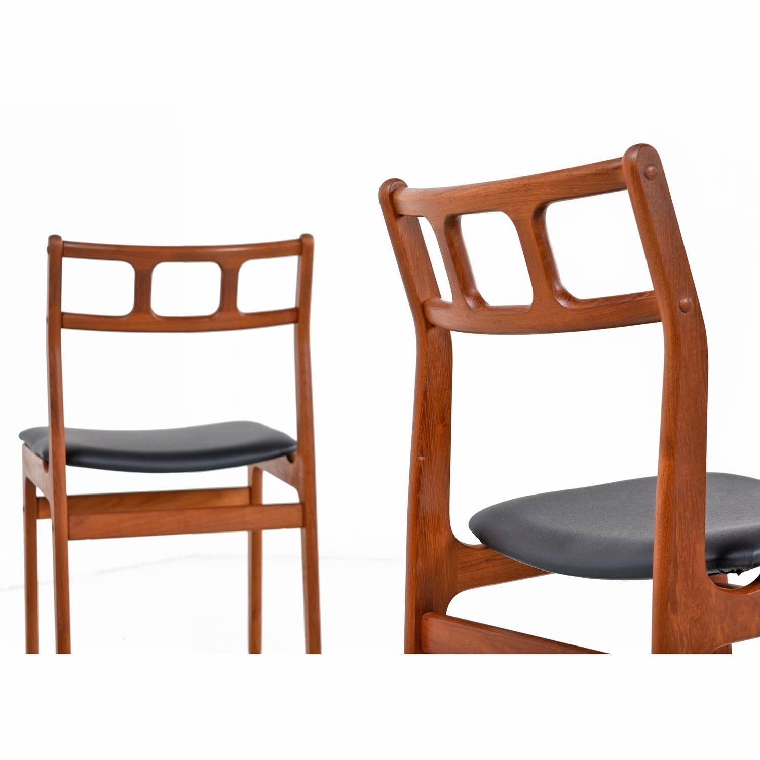 Set of four solid teak vintage Danish modern dining chairs. The quintessential Scandinavian design features a Minimalist approach with two contoured lateral spanners to support the back. The seats have been updated with new high quality vinyl