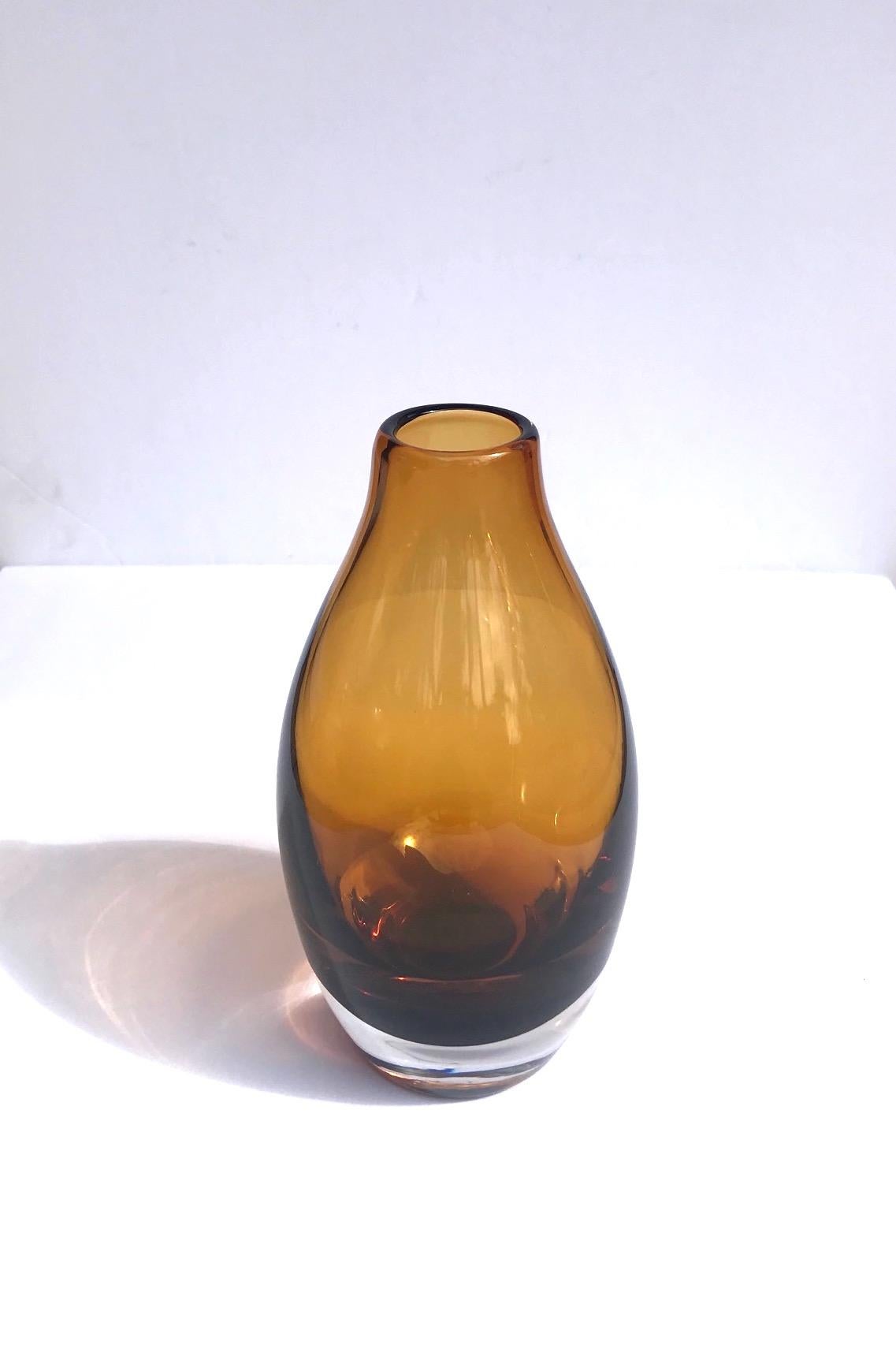 Mid-Century Modern hand blown glass vase in hues of amber. Features submerged cased glass in amber floating over a translucent base. Vase has a bottle glass shape with freeform shortened stem.