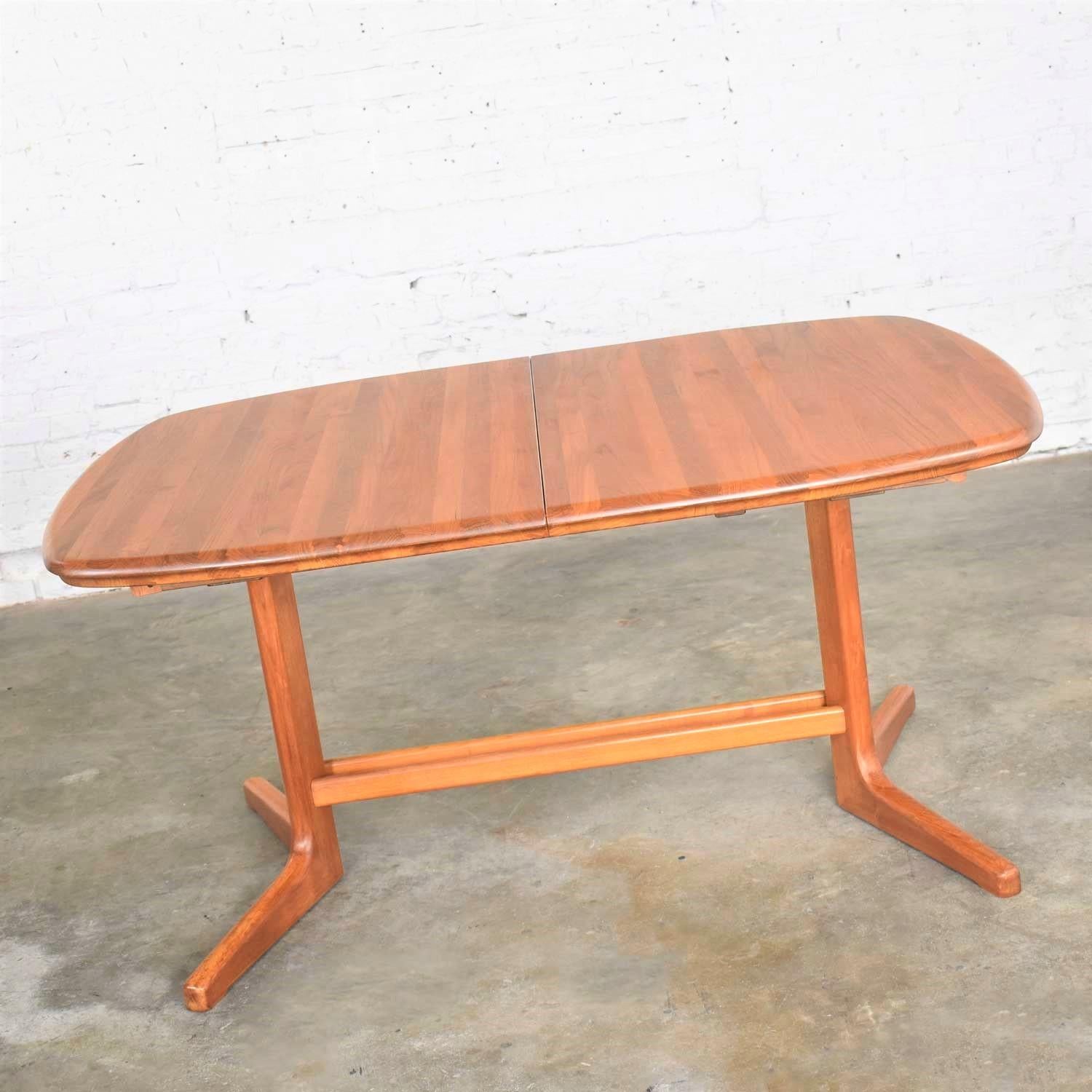 Handsome Scandinavian Modern oval expanding dining table in teak with 2 leaves and attributed to Dyrlund. It is in fabulous vintage condition. The top, including the leaves, has been completely and expertly refinished and the base finish has been