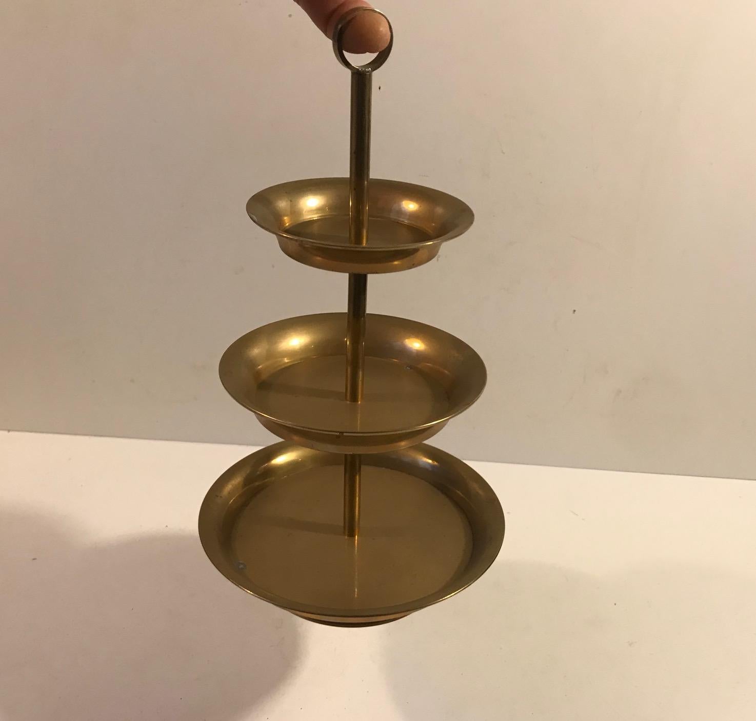 Charming cake stand with practical 'finger hole' handle. Its made entirely from solid brass. Unknown Scandinavian maker in the style of Svenskt Tenn, circa 1970.
