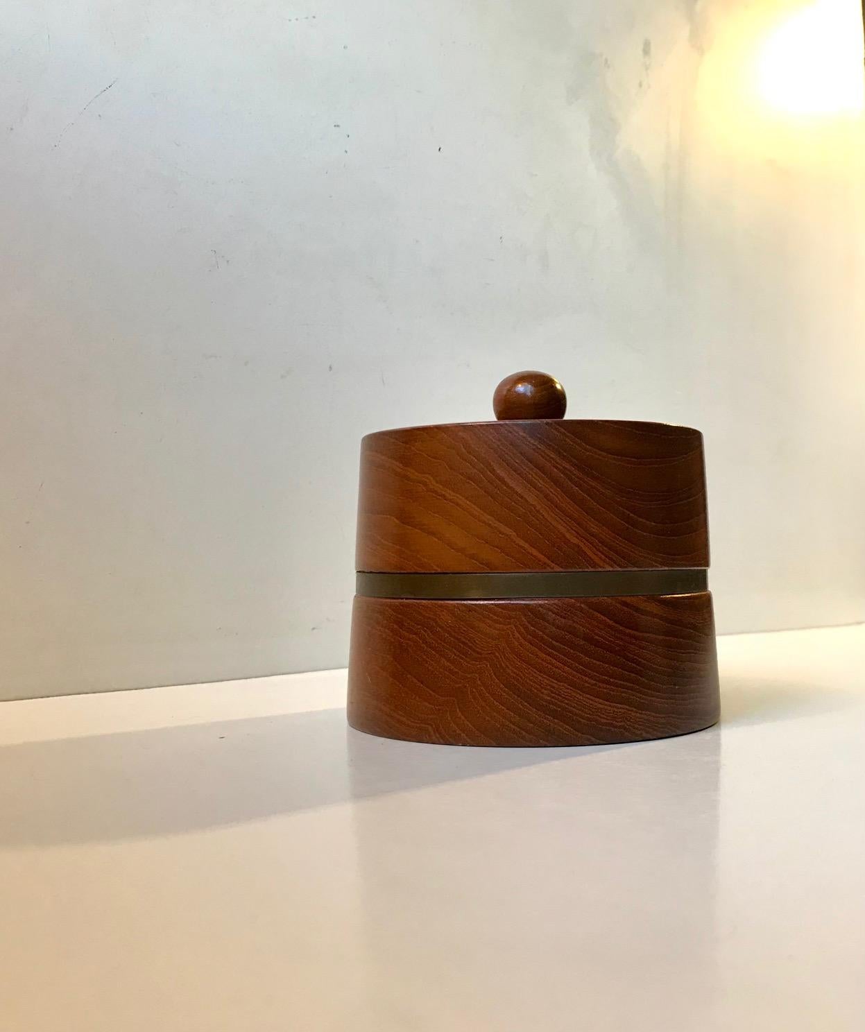 A wellmade jar for tobacco or tea. Its made from solid stacked teak and features a decorative 'belt' in patinated brass. It was designed and made by Christer design during the 1960s in a style reminiscent of Kay Bojesen and Henning Koppel.