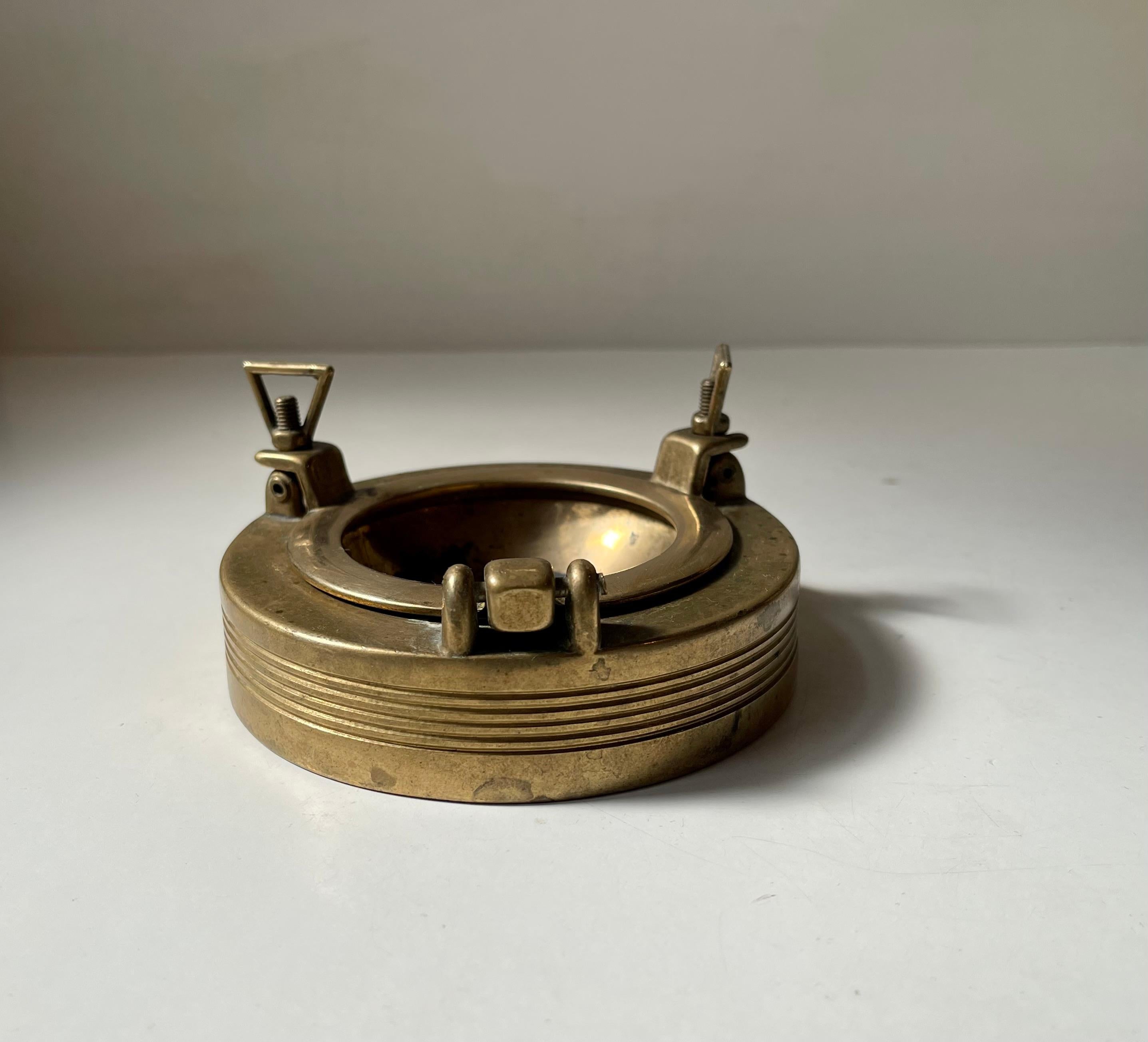 A novelty in-/outdoor ashtray in the shape of a ships porthole. It is made from solid brass that has patinated over the years. Made in Scandinavia during the 1950s. Measurements: D: 11 cm, H: 3/5,5 cm.