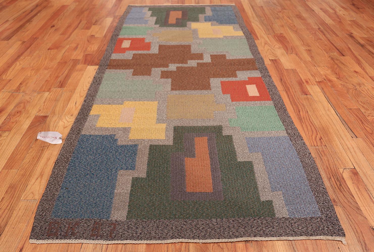 Woven in a bold right-angle style, this striking Swedish area rug is like a visual etude that explores the effects of color and form and investigates the magnetic relationship between negative and positive space. The elongated rectangular