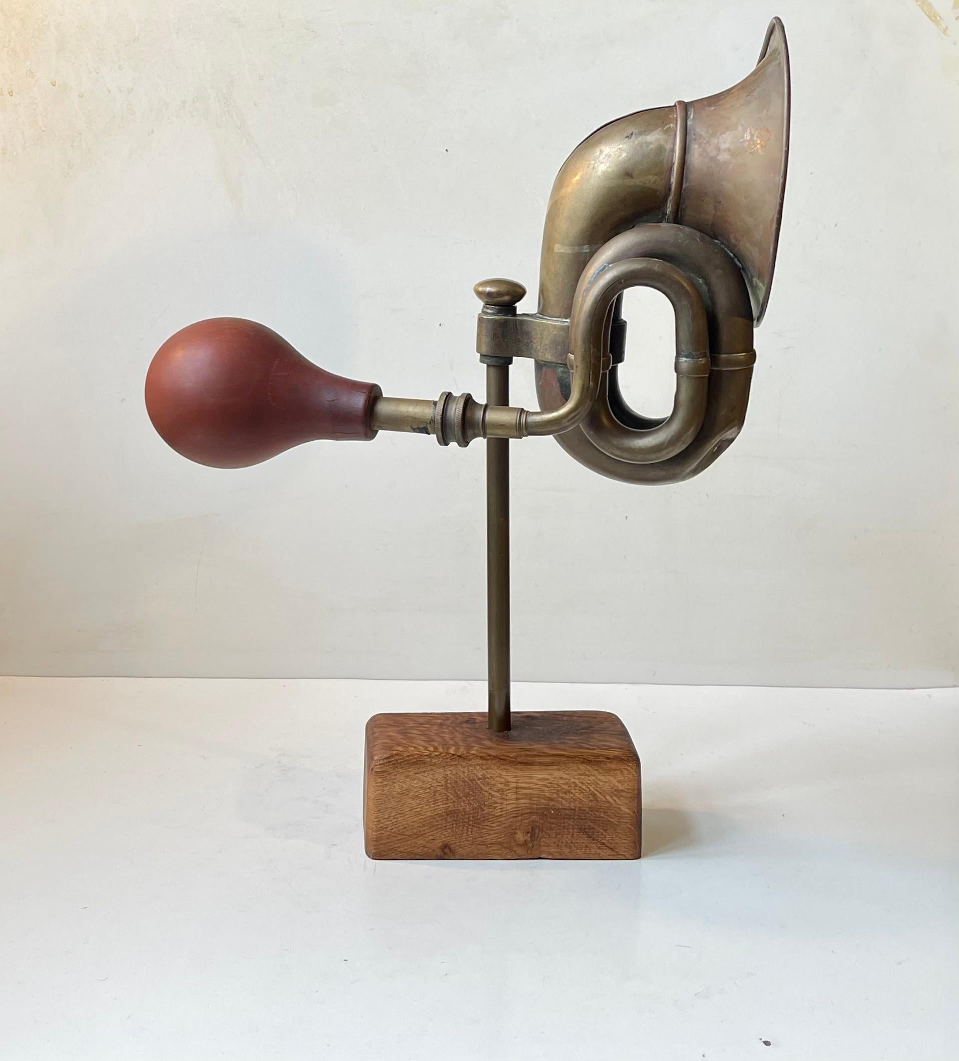 Unusual mounted object in the shape of a antique/1920s brass vehicle horn set on a brass rod and a patinated oak rectangular base. Unknown Danish sculptor/artist circa 1970-80. There is still a bit of noise to the horn when the rubber squeezer is