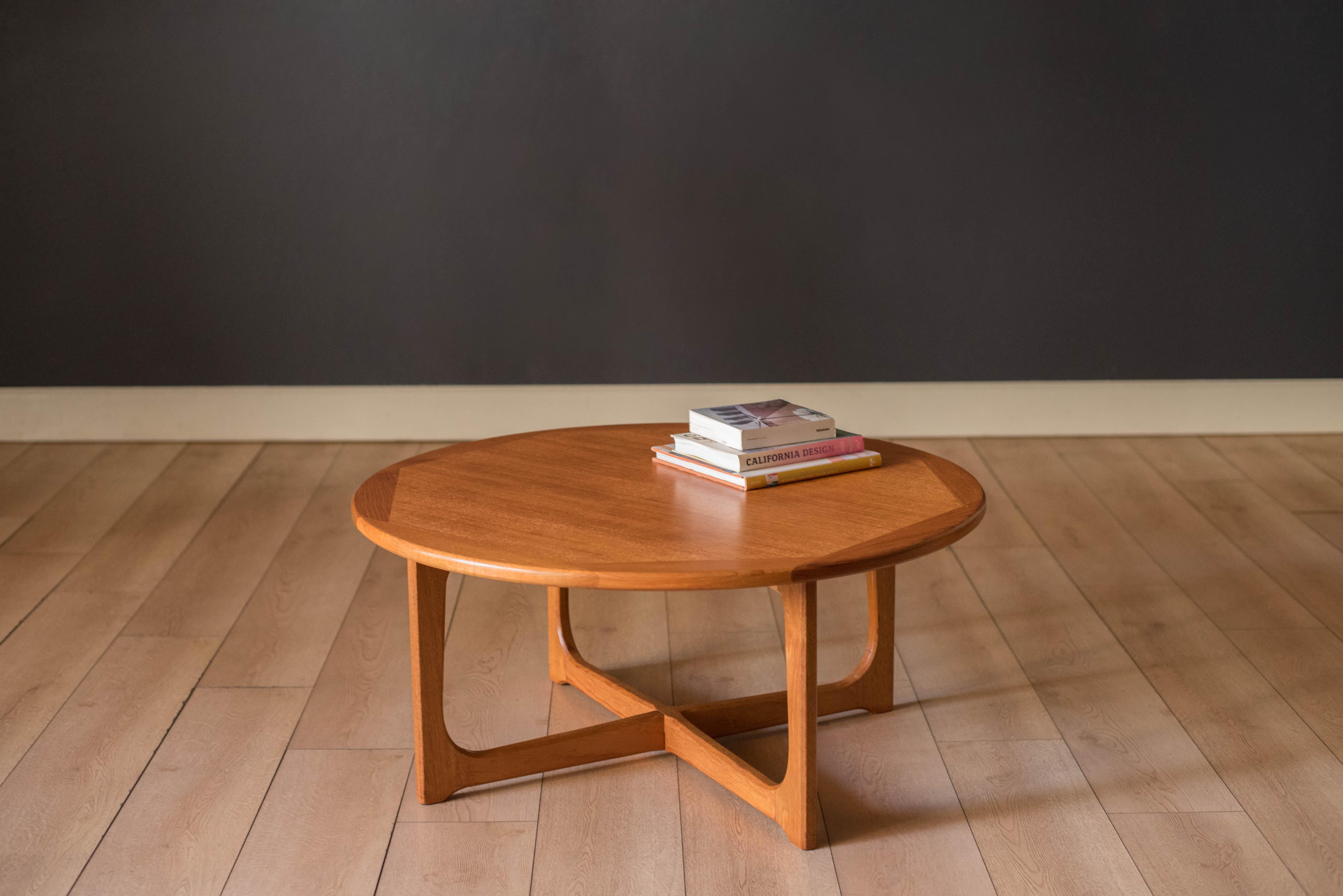Moderner runder Couchtisch aus Teakholz aus der Mitte des Jahrhunderts, ca. 1970er Jahre. Die kontrastierenden Massivholzkanten bilden ein überlappendes Design. Dieses Stück ist niedrig und wird von einem stabilen skulpturalen X-Sockel getragen. 


