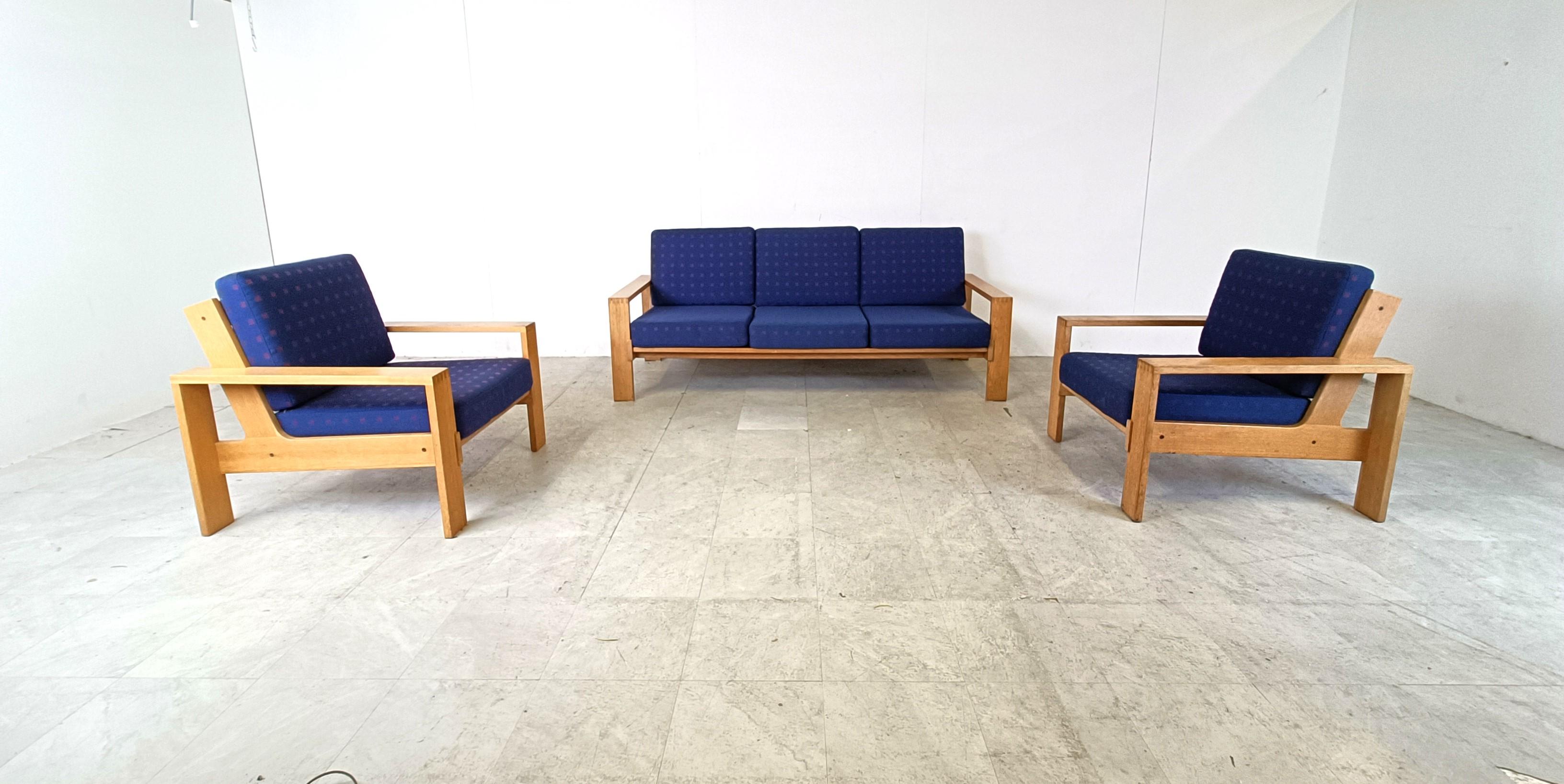 Sofagarnitur im Vintage-Stil, bestehend aus zwei Sesseln und einem dreisitzigen Sofa.

Das Design ähnelt den Asko 'Bonanza' Sofas mit ineinander greifenden Holzrahmen.

Die Sofas haben ihre originalen blauen Stoffkissen. 

Sehr guter Zustand

1970er