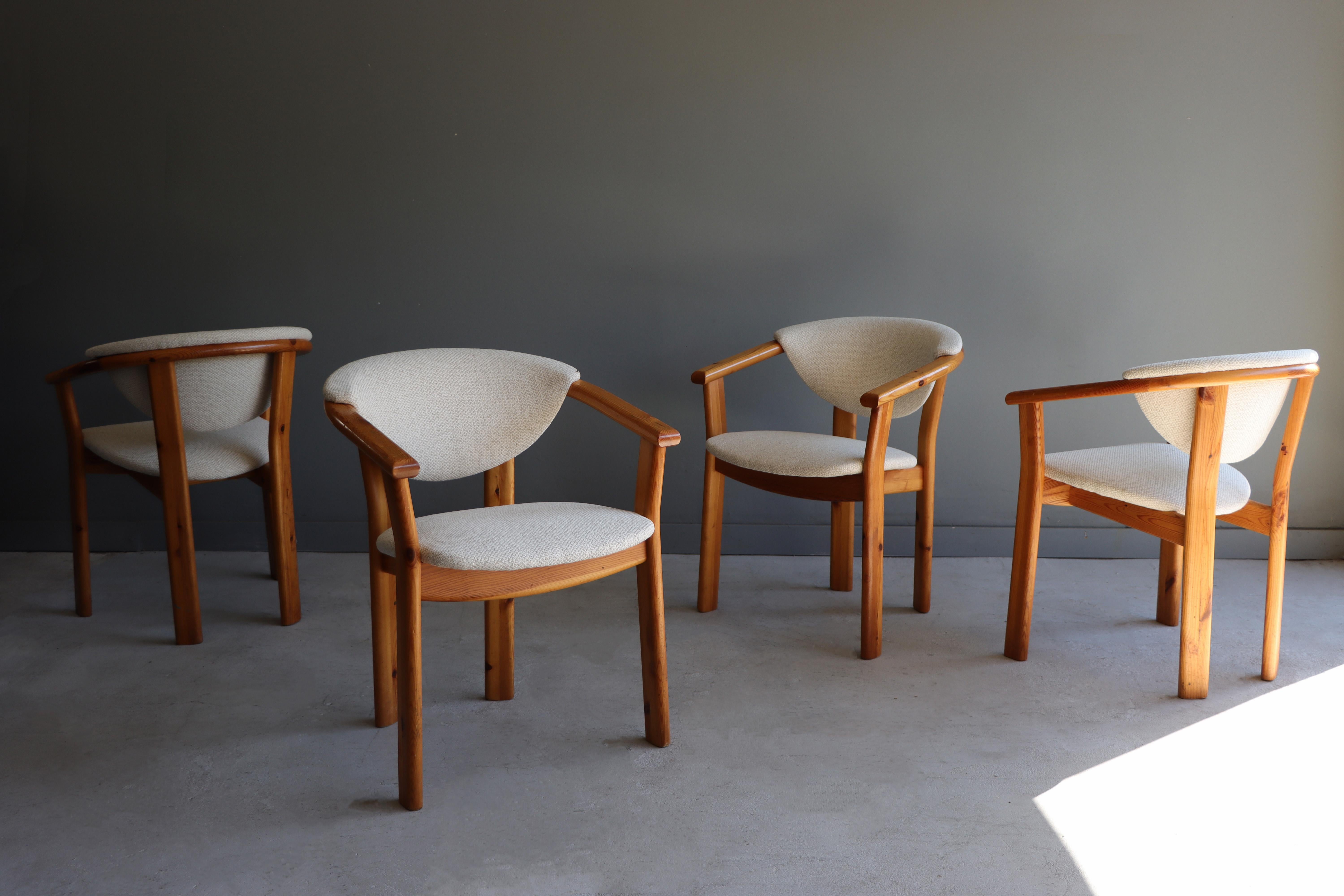Beautiful set of vintage Scandinavian armed dining chairs. These sculptural chairs are executed in solid pine and have been reupholstered in Knoll Whitewall fabric. While the manufacturer is unknown, these chairs check all the boxes. Each backrest