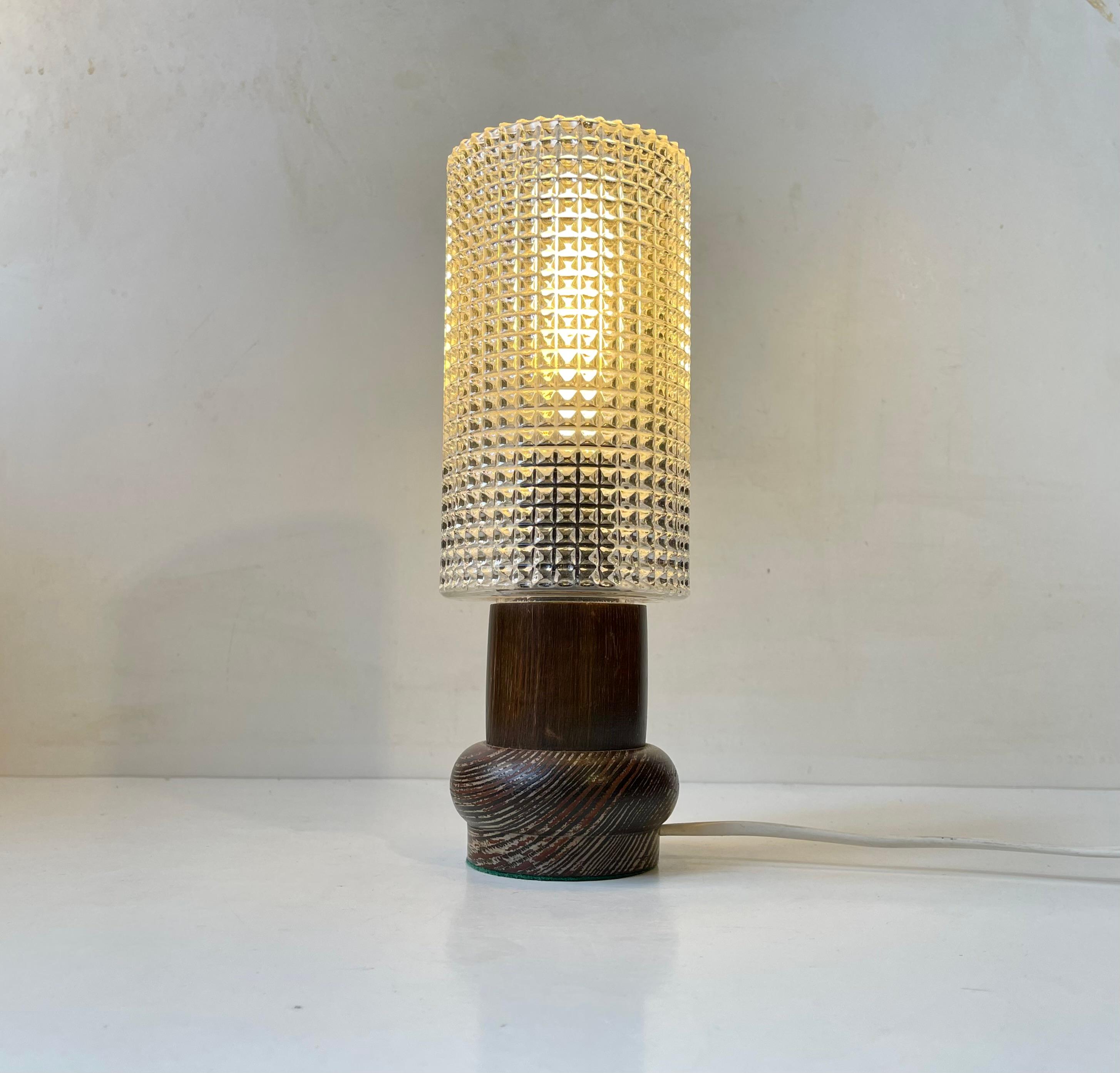 Small unusual table light fashioned from lacquered/dark zebra wood and installed with a cylindrical shade in diamond pattern glass. Unknown Scandinavian maker circa 1970-80. Measurements: H: 27 cm, Diameter: 10 cm (shade).  For the US. It will come