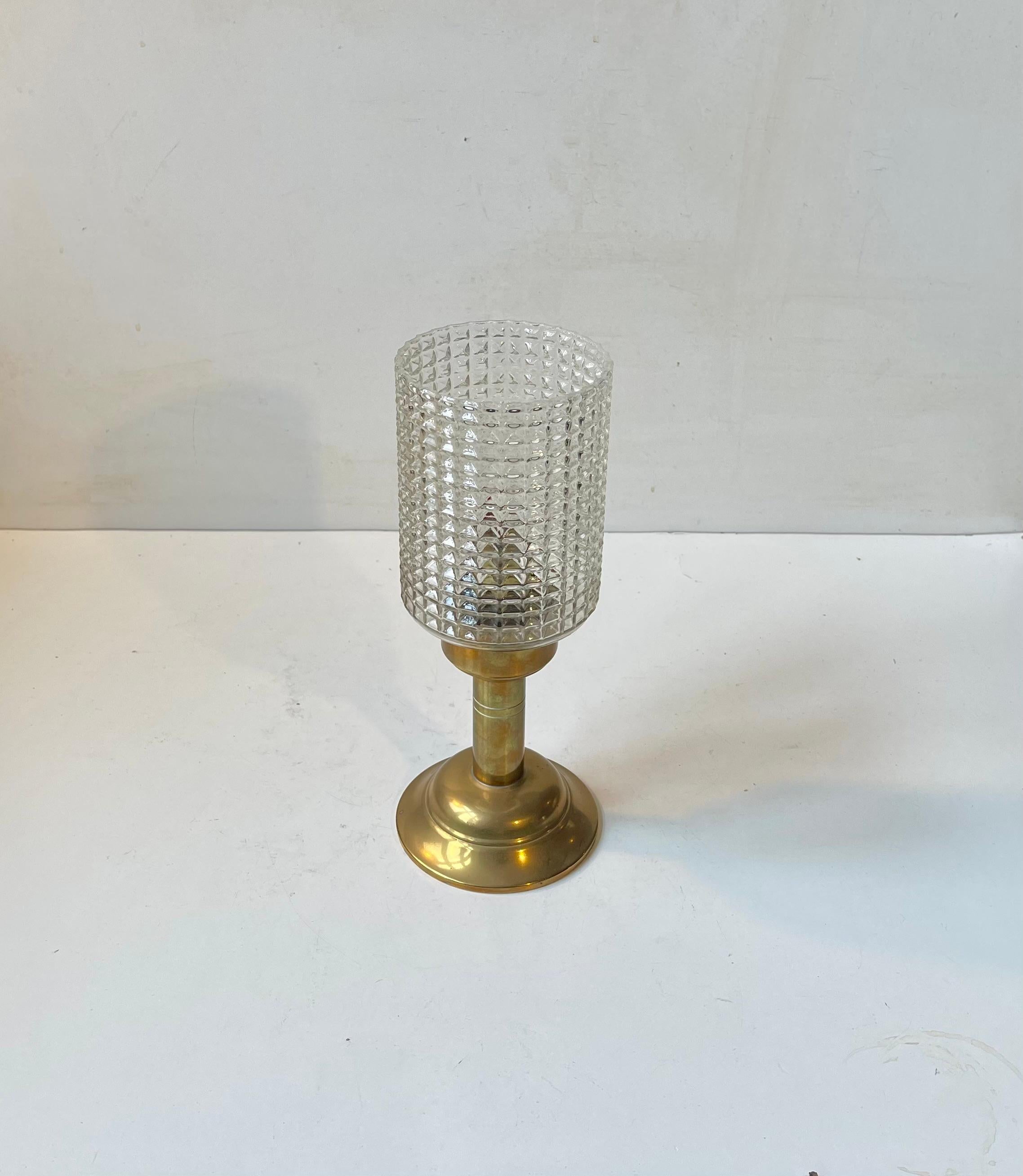 In the style of Hans Agne Jakobsson comes this stylish oil lamp fashioned from solid patinated brass and featuring and diamond-pattern pressed clear glass shade. It was made anonymously in Scandinavia during the 1960s or 70s. It is well-kept and in
