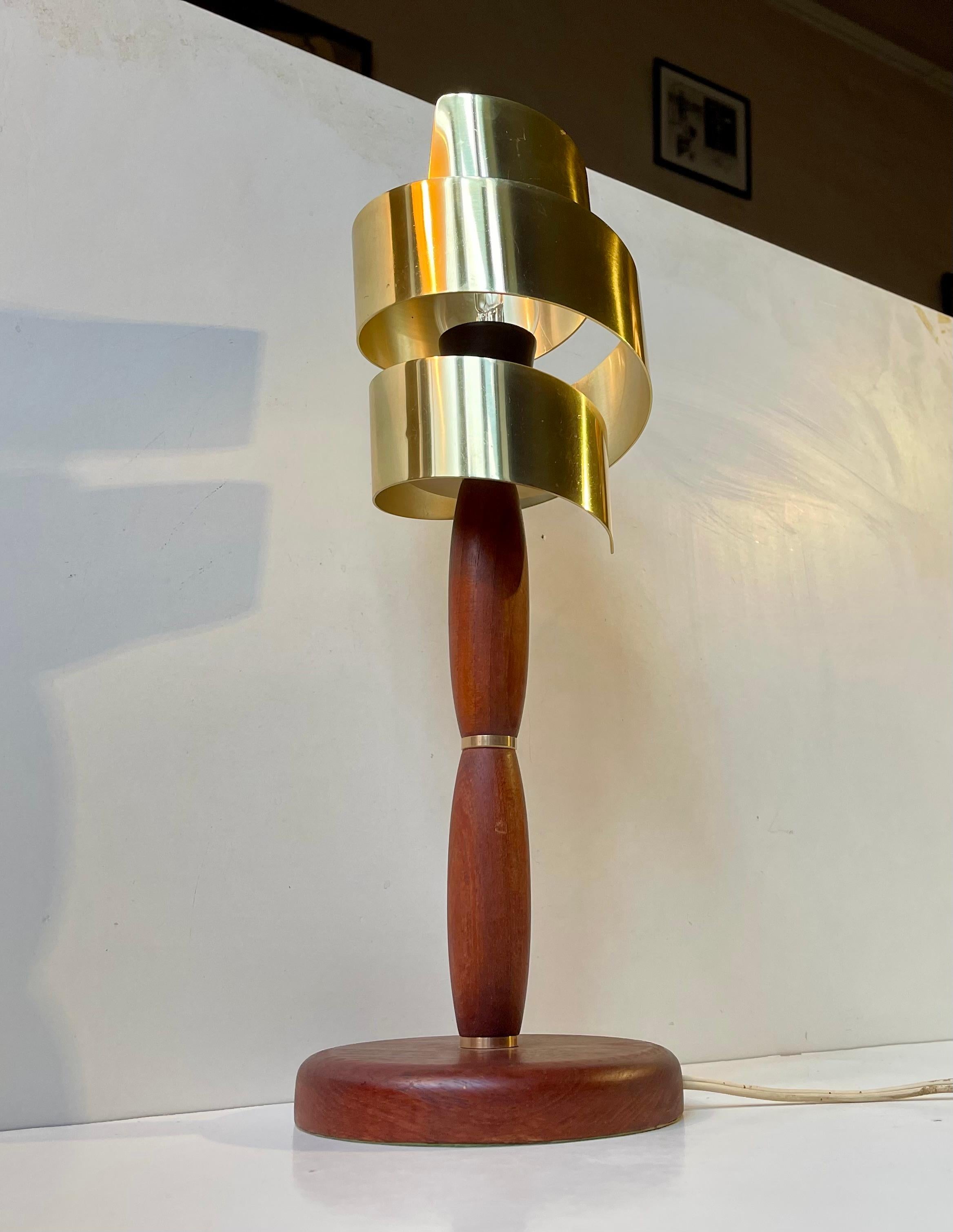 Table Lamp composed of a solid teak base and rod with solid brass accents highlighting the organic curves of the rod. It was designed and manufactured anonymously in Scandinavia during the 1960s in a style reminiscent of Hans Bergstrom and Jo
