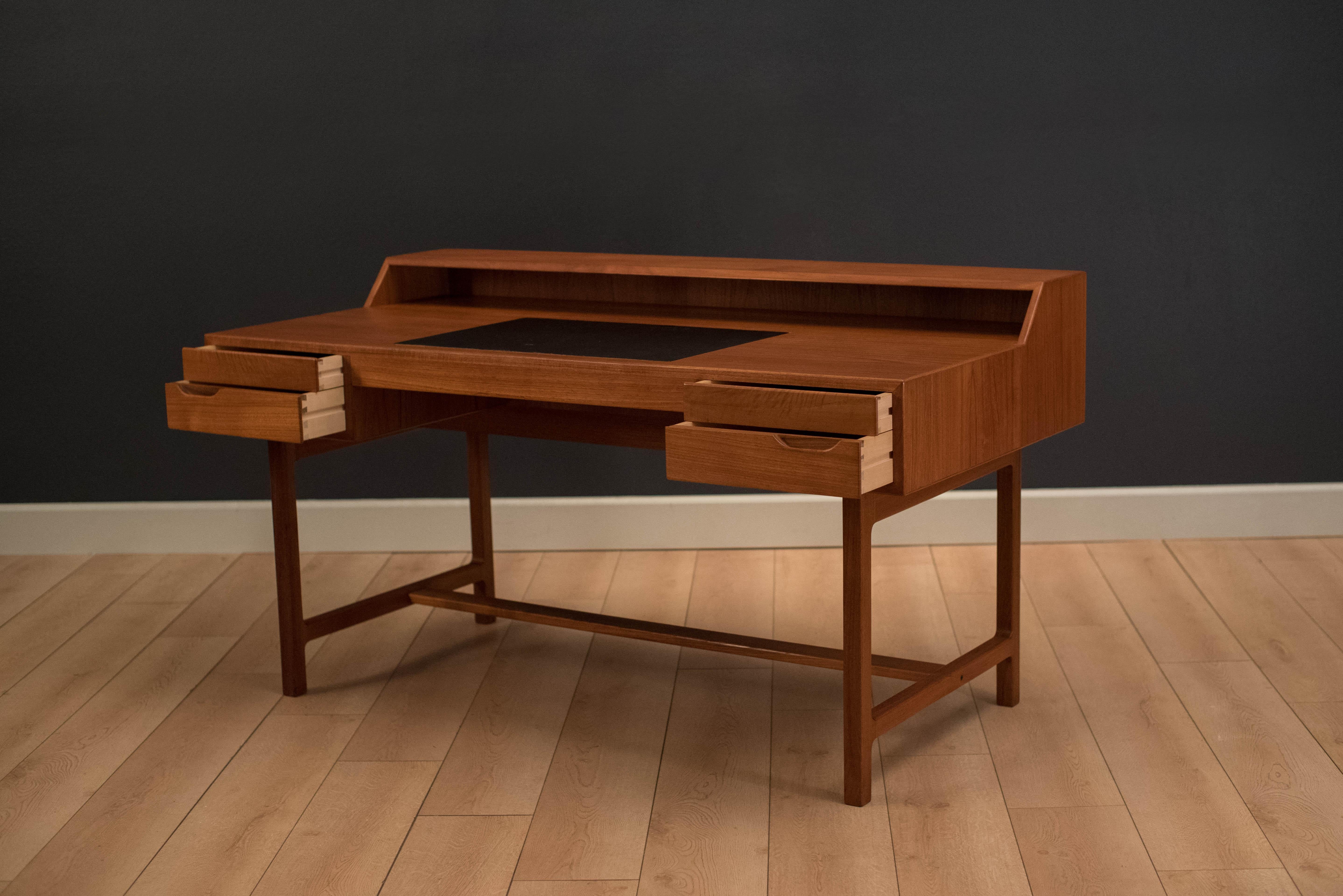 Mid-Century Modern writing desk in teak, circa 1960s. This piece has a wide desktop surface area equipped with a leather writing pad. Open cubby space is provided for extra storage. This desk displays well from any angle with a finished backside.