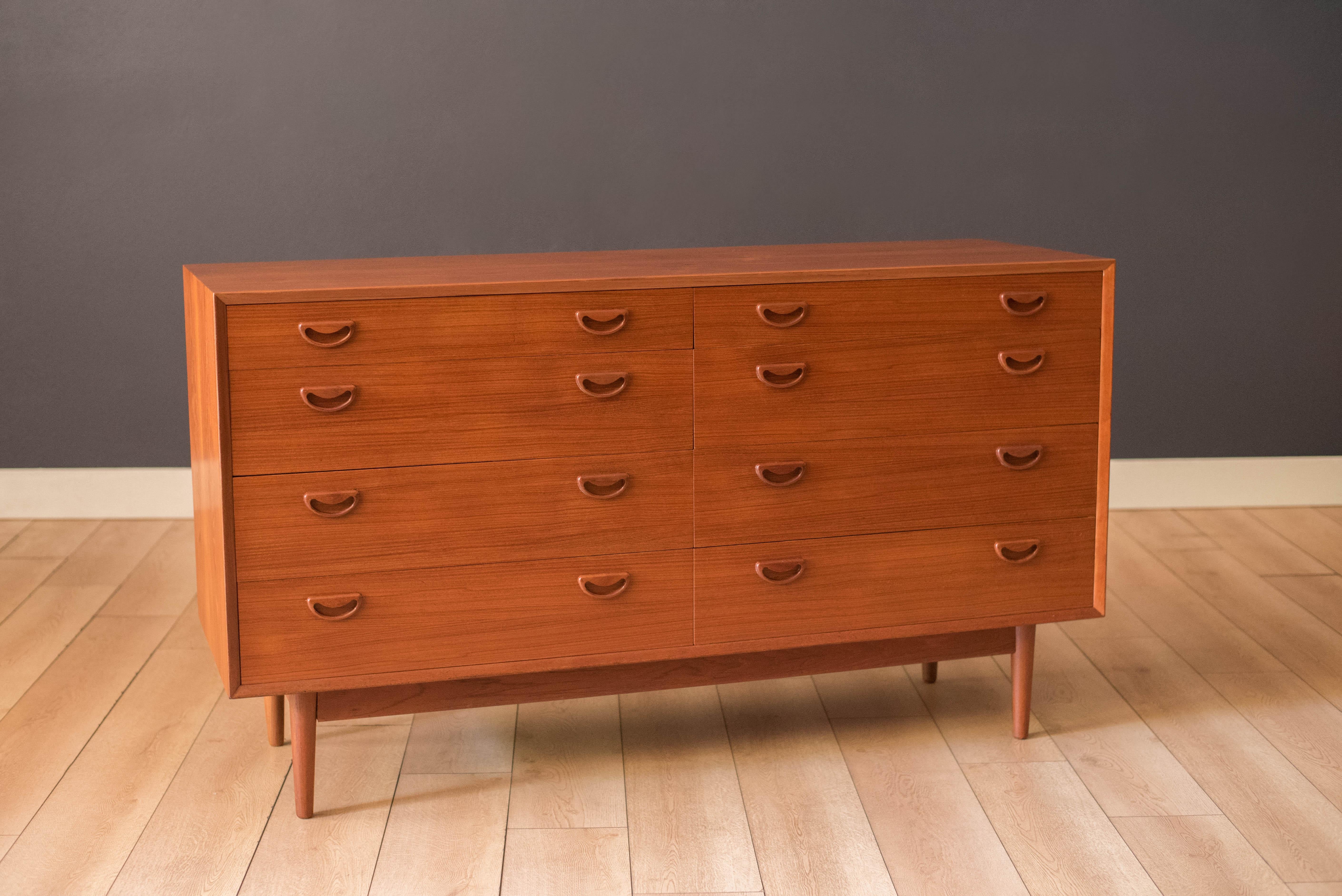 Mid century modern lowboy dresser in teak circa 1960's. Features natural bookmatched grains and solid wood sculpted handles. Offers plenty of storage space equipped with eight drawers in various sizes. Matching tall highboy dresser available in