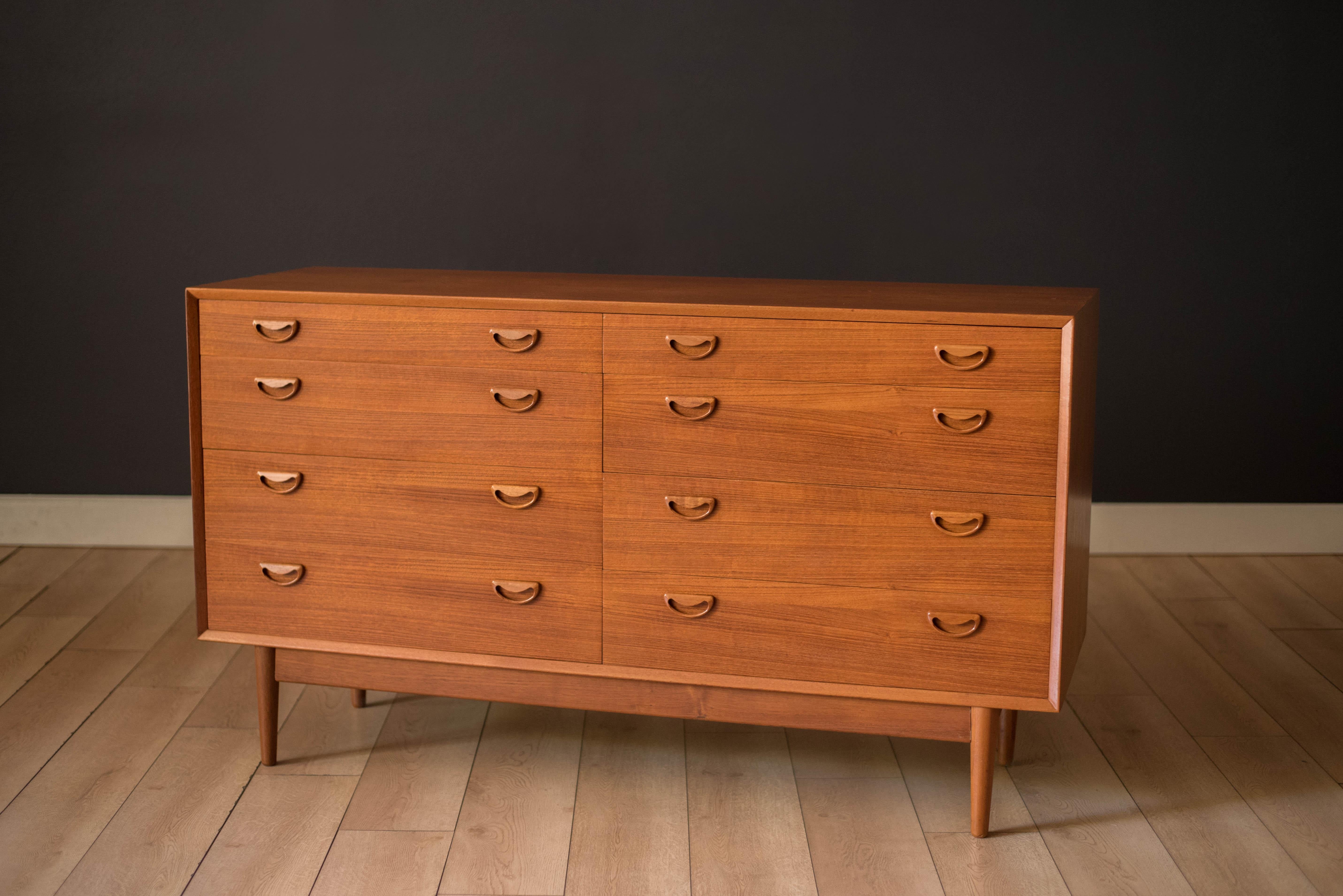 Mid century modern lowboy double dresser in teak circa 1960's. Features natural bookmatched grains and solid wood sculpted handles. Offers plenty of storage space equipped with eight drawers in various sizes. 