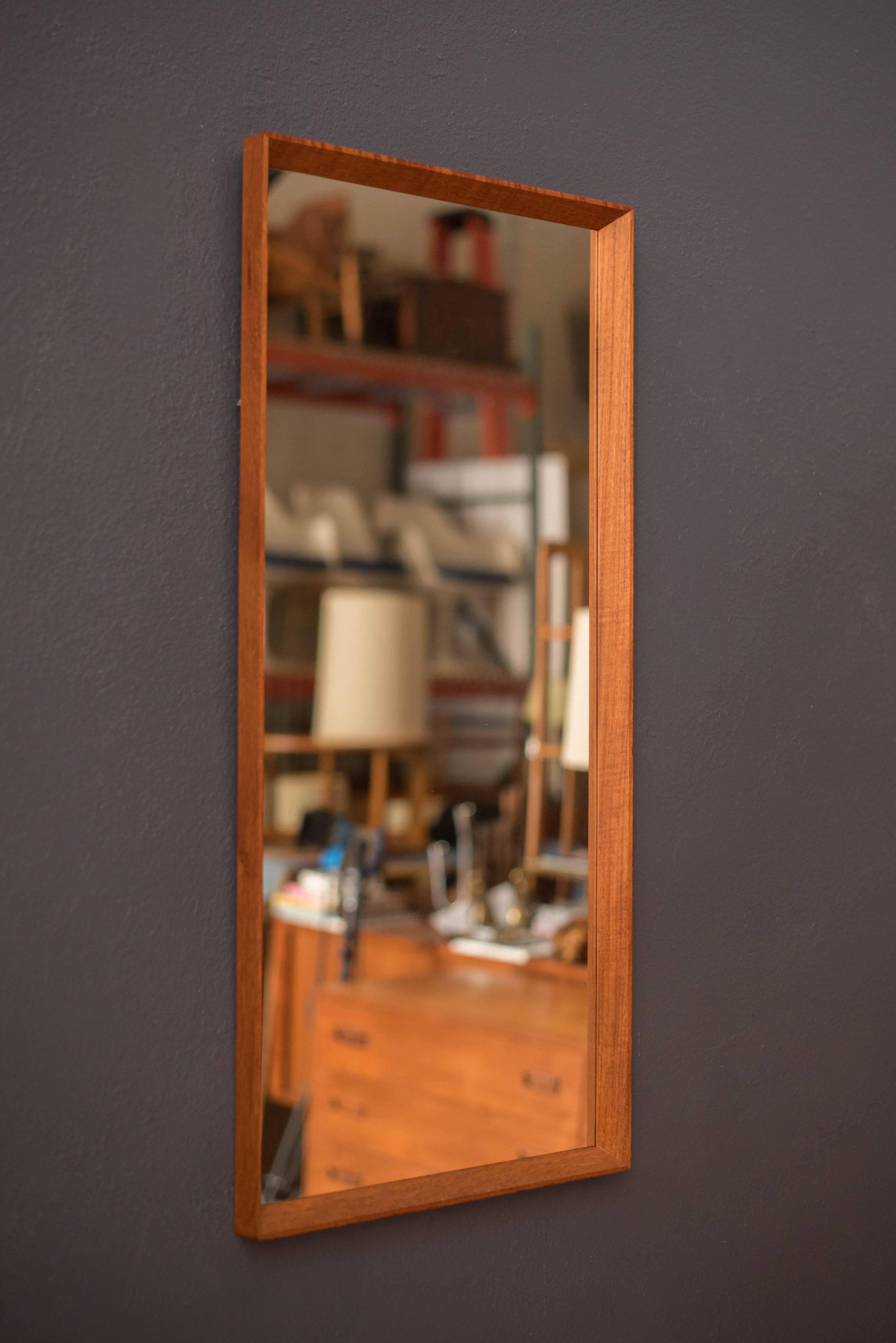 Specchio da parete sospeso in teak della metà del secolo scorso, anni '60 circa. Questo elemento decorativo d'accento mostra le venature naturali del legno con una sottile cornice rettangolare. È perfetto per l'ingresso, la camera da letto, il bagno