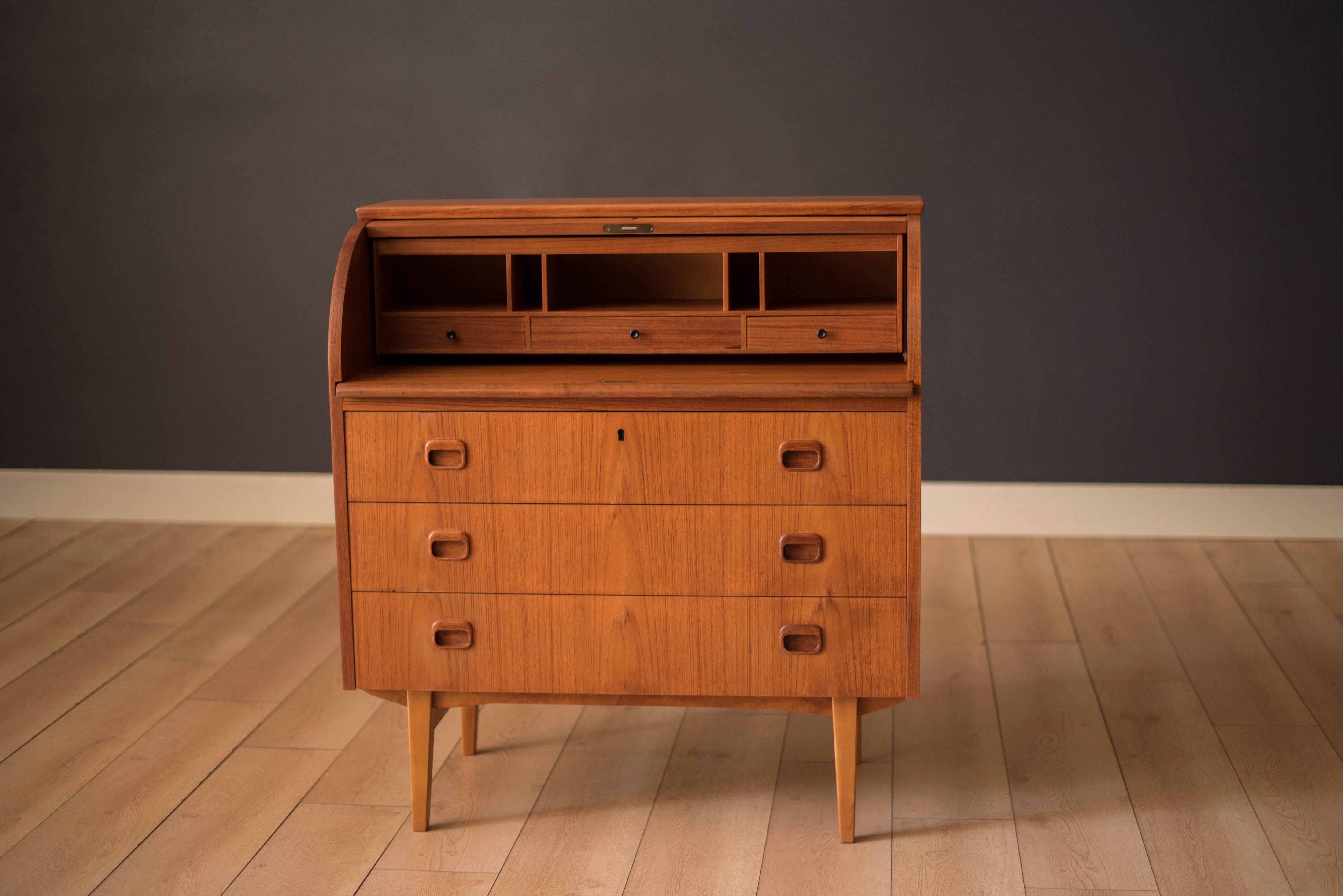 Mid Century Modern secretary desk in teak designed by Egon Ostergaard for Svensk Mobelindustri, Sweden. This piece is equipped with three deep storage drawers with sculpted handles. Features a stunning teak grain roll top door that reveals a slide