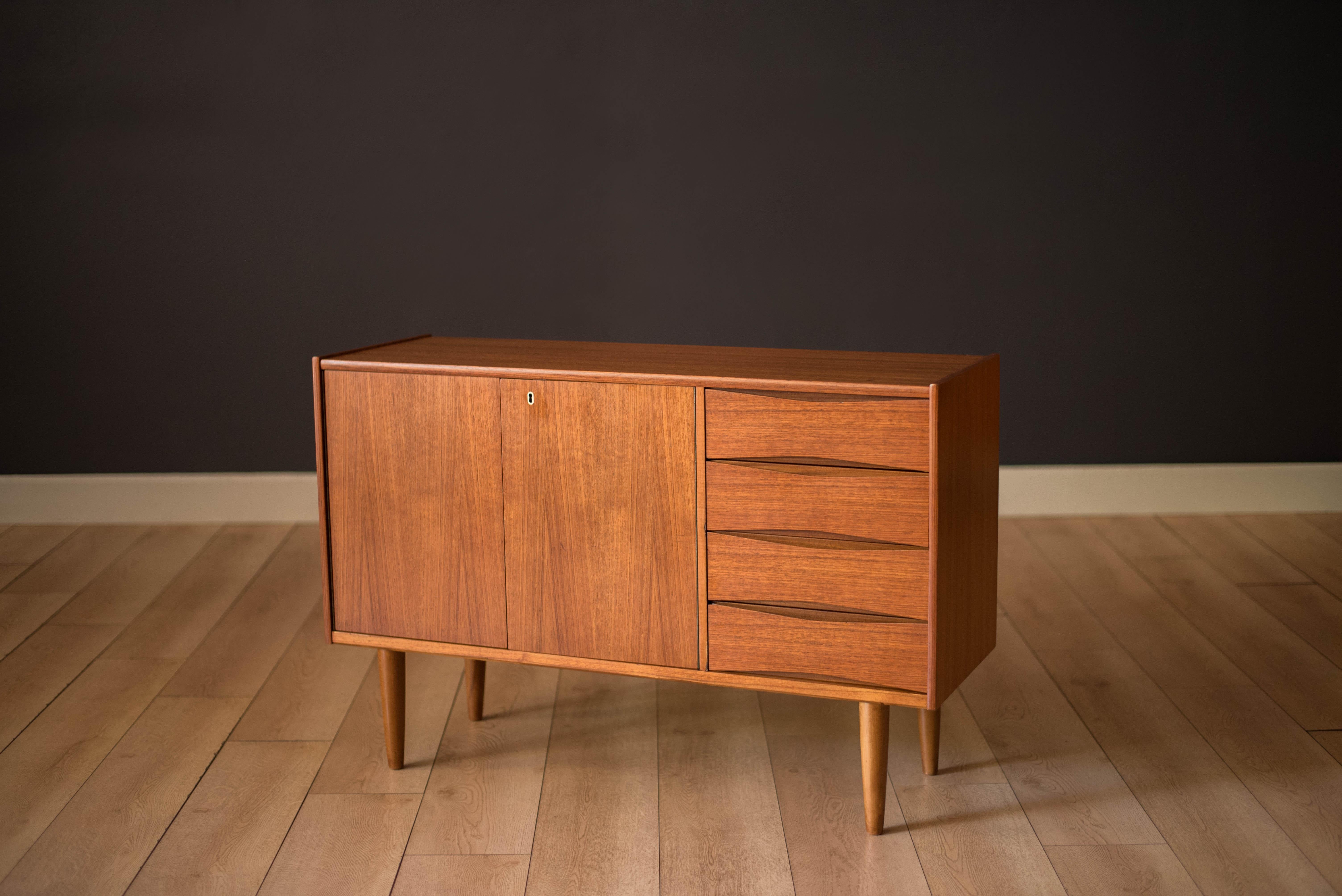 Mid-Century Modern sideboard credenza in teak designed by Fredrik Kayser for Skeie & Company of Norway, circa 1960s. This versatile piece is equipped with four drawers crafted with sculpted handles. The locking cabinet features swing out doors