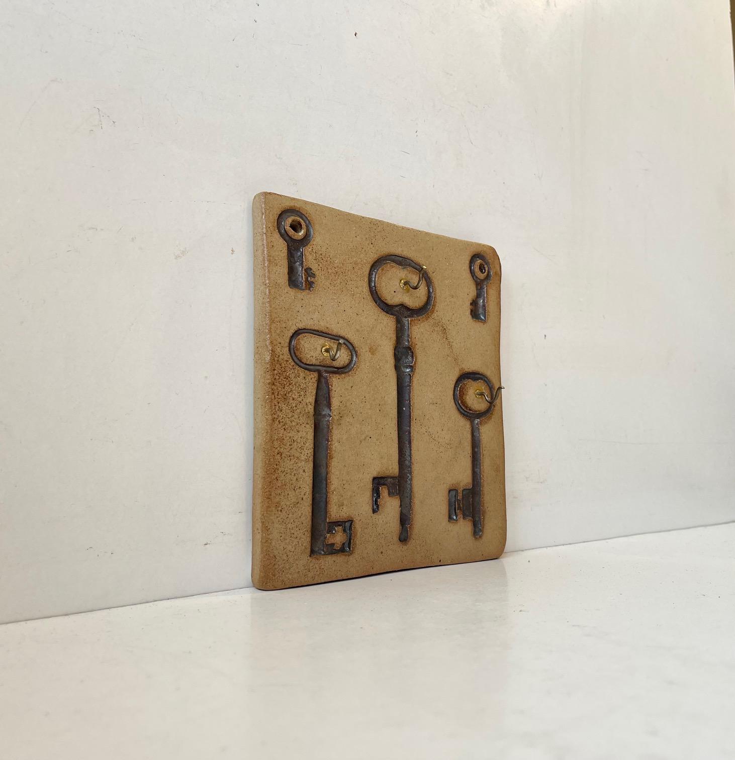 Ungewöhnlicher Schlüsselhalter aus Steingut für die Wandmontage. Verziert mit Abdrücken von verschiedenen Schlüsseln. Entworfen und hergestellt von Ulla Lønow in Dänemark, um 1970. Abmessungen: 16,5 x 15 x 1,5 cm.