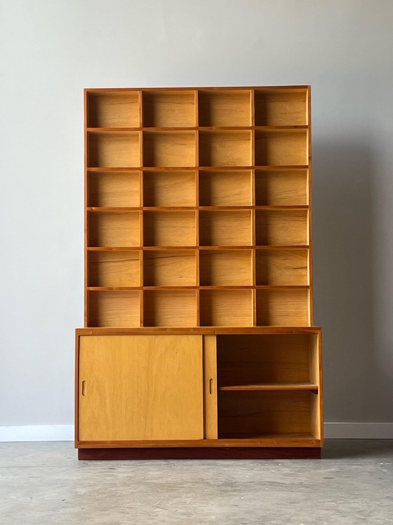 Vintage unique Scandinavian cabinet with attached cubby shelves. The bottom credenza portion has two sliding doors with carved oval handles. There isa internal shelf within the credenza, ideal for storage. The upper section features twenty-four