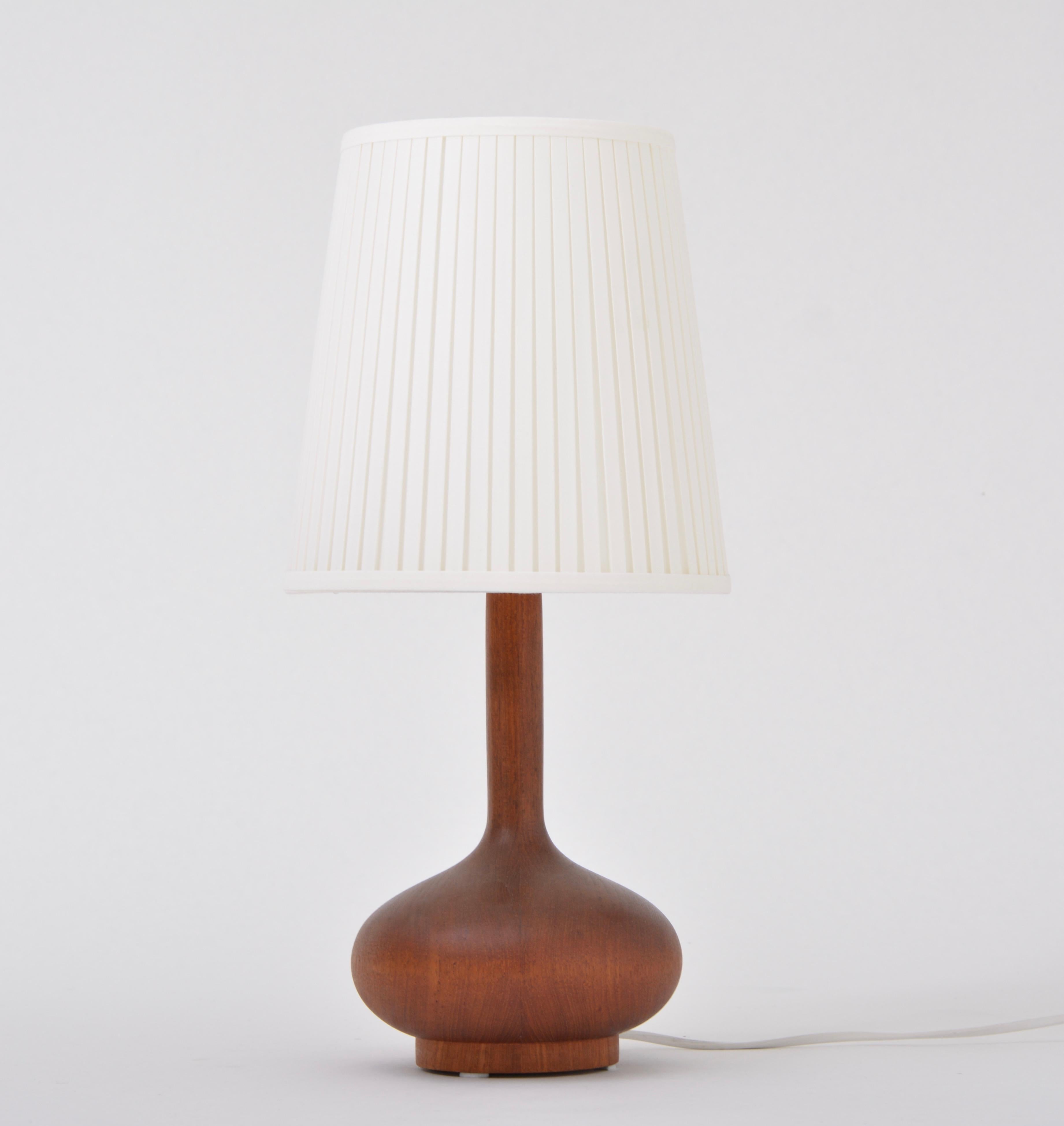 This table lamp was produced in the 1960s in Scandinavia, probably in Denmark. The base is made of teak wood. The lamp has been rewired with a switch and has a new socket and shade.