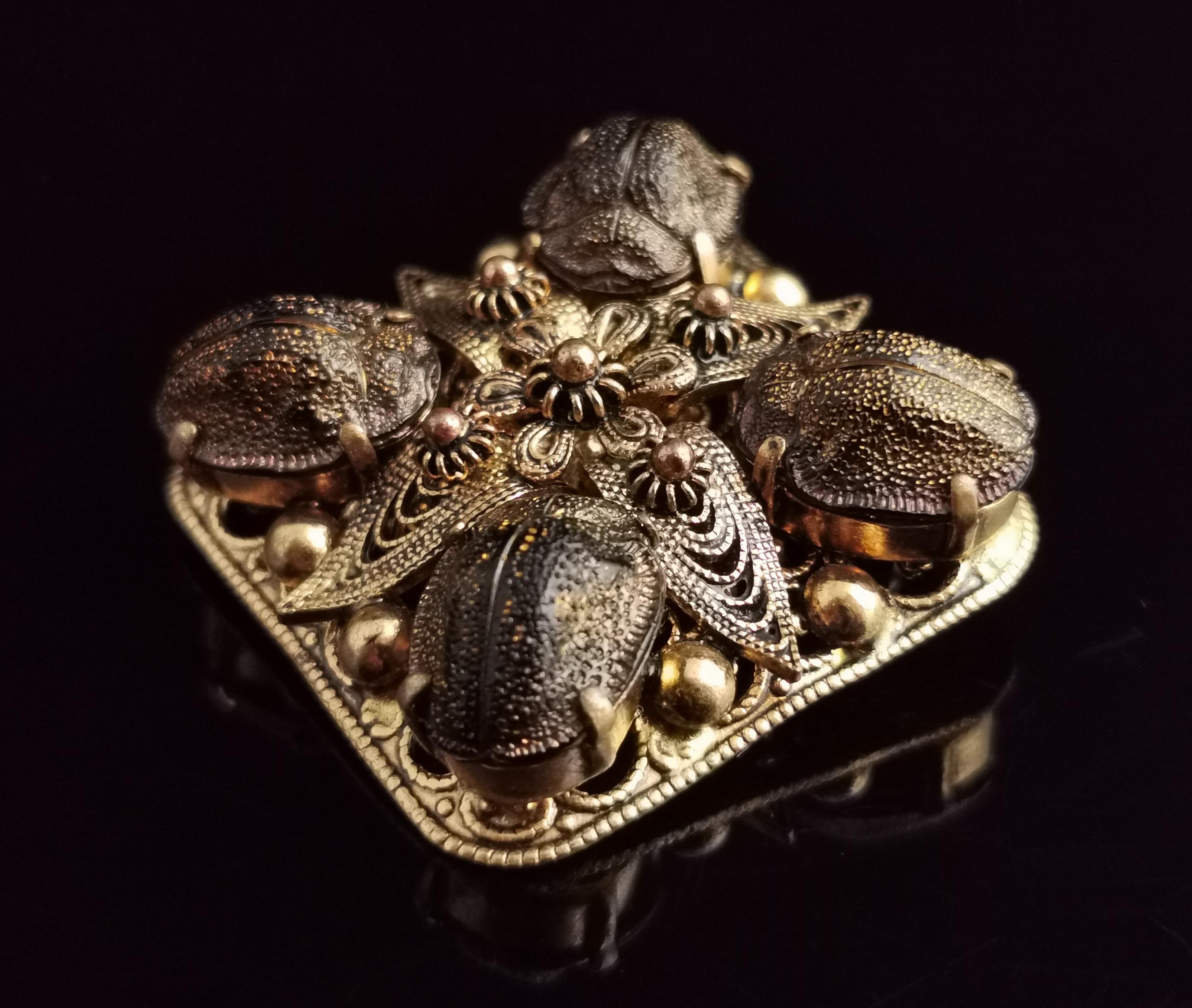 A beautiful vintage Egyptian revival real scarab beetle brooch.

It is a diamond shape or square shape depending on which way you would like to wear it.

Made from gilt metal with cannetille accents, the brooch has four real dried scarab beetles