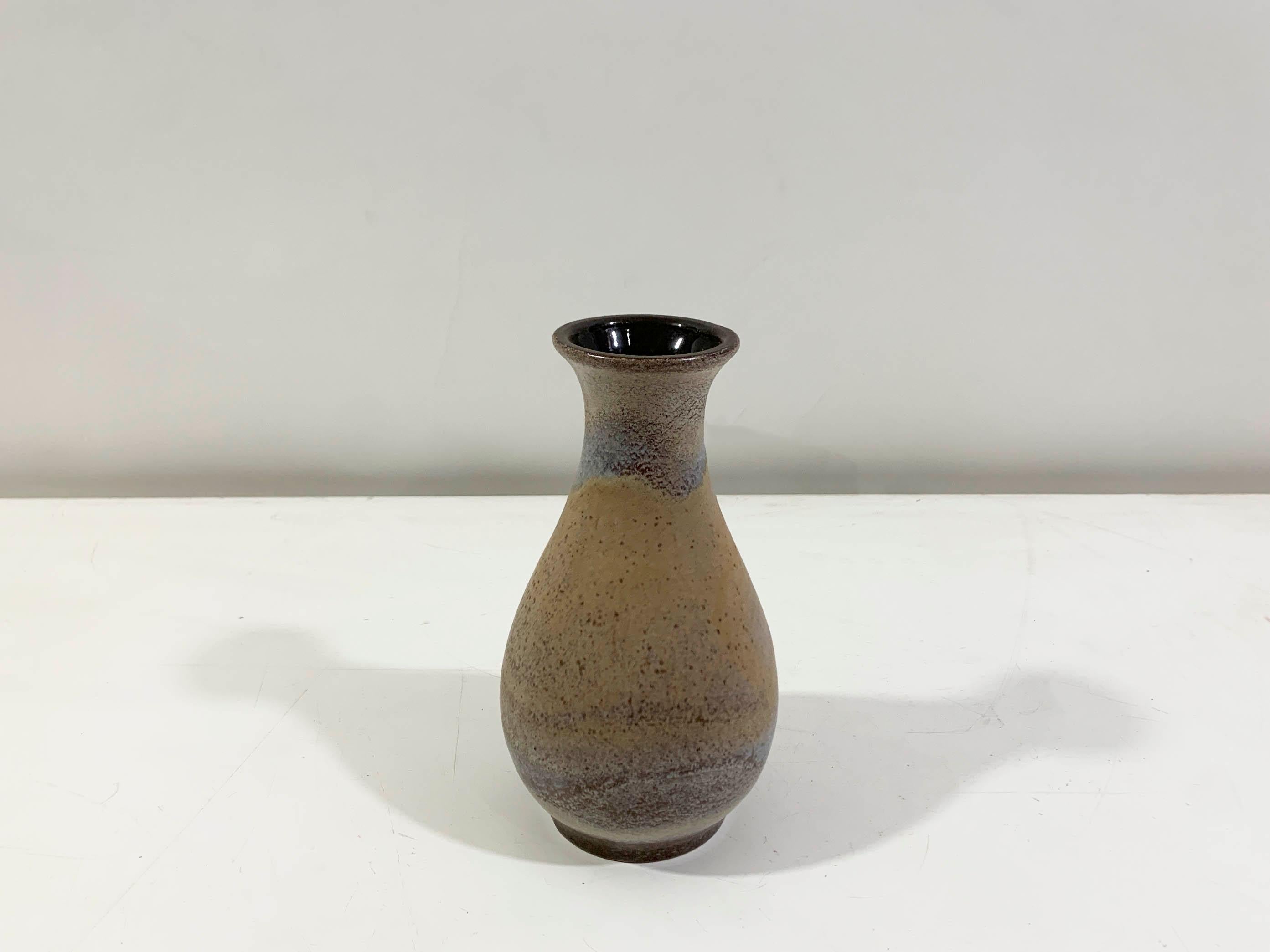 Ce vase vintage en céramique d'Allemagne de l'Ouest, datant du milieu du 20e siècle, présente une forme bulbeuse classique avec un col étroit et un bord légèrement évasé. Elle présente une glaçure mate et mouchetée dans les tons de brun avec de