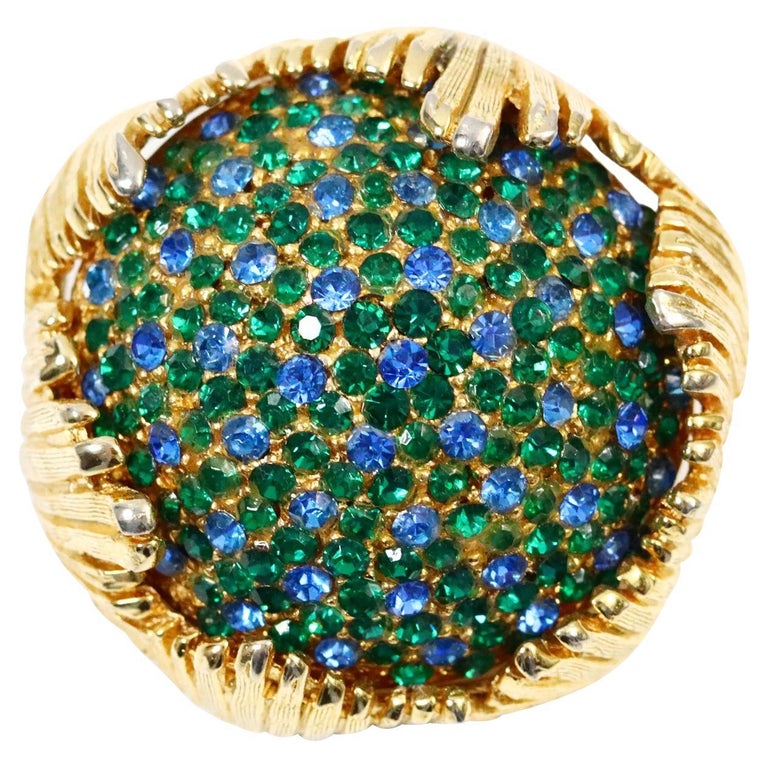 Vintage Schiaparelli Gold Brooch With Blue and Green Crystals Circa 1960s. This magnificient piece is round and domed. The crystals are set inside of the gold round dome that is itself diferent shapes of teh gold ging up around it. You can wear as a