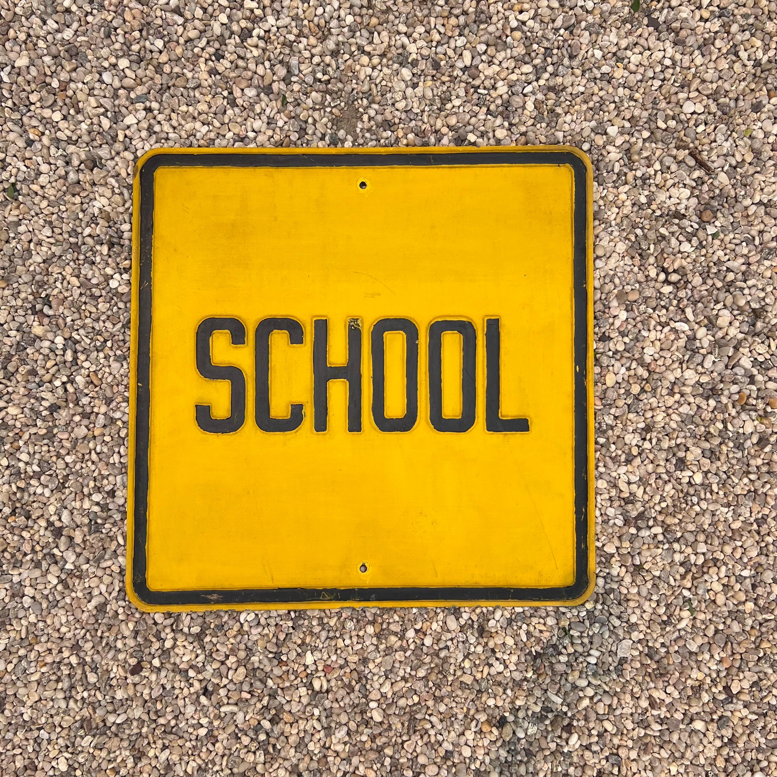 Distressed vintage embossed School sign. Reads 