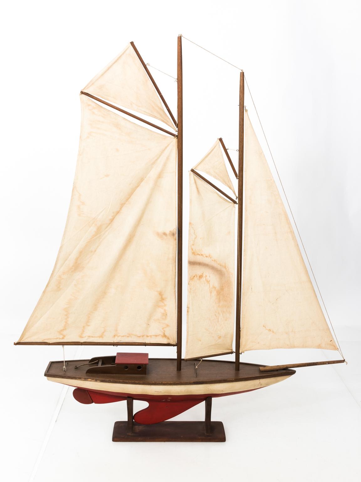 Vintage model of a schooner with original red and white paint, circa 1950s. Please note of wear consistent with age including discoloration to the fabric of the sails and faded paint. Made in the United States.
 
