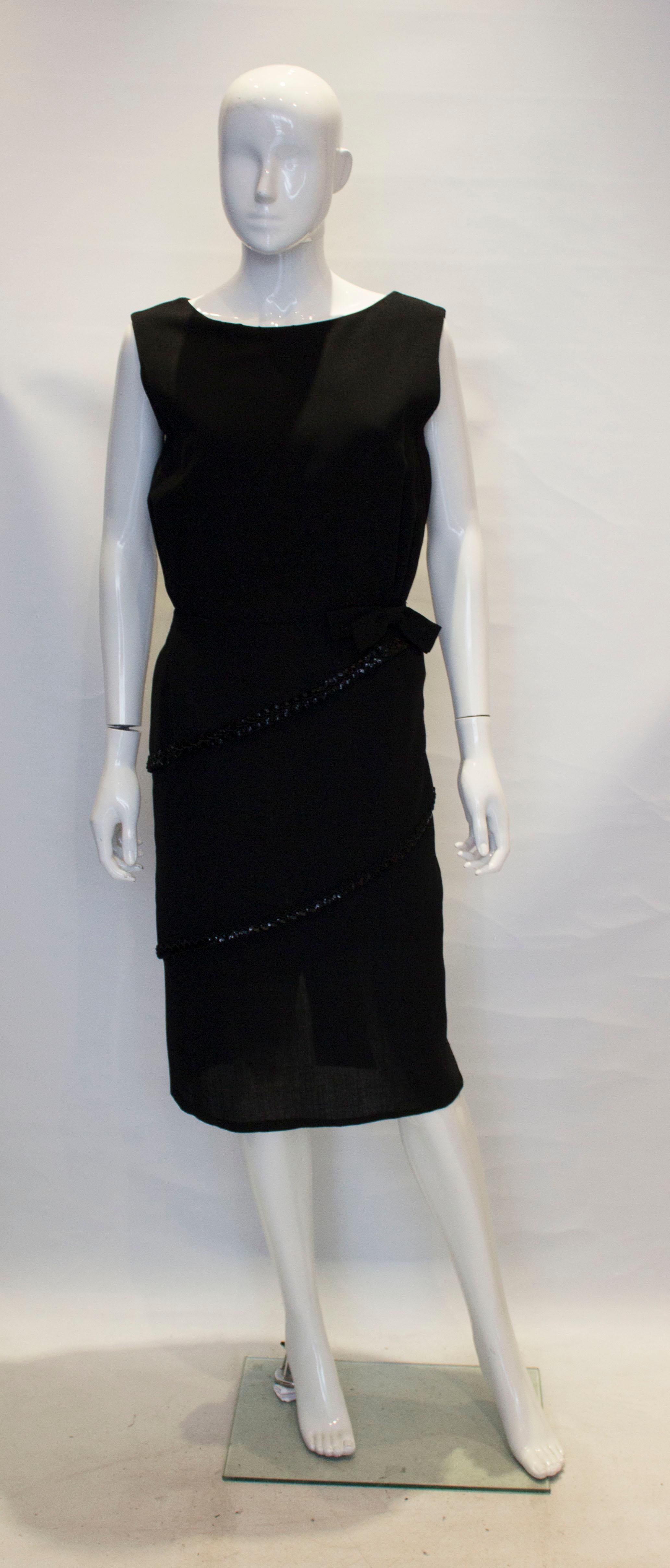 A super  vintage little black dress by Schroder Wolf.  The dress has asymetric layers with sequin detail ,gathering under the bust, and a central back zip. It is fully lined. 