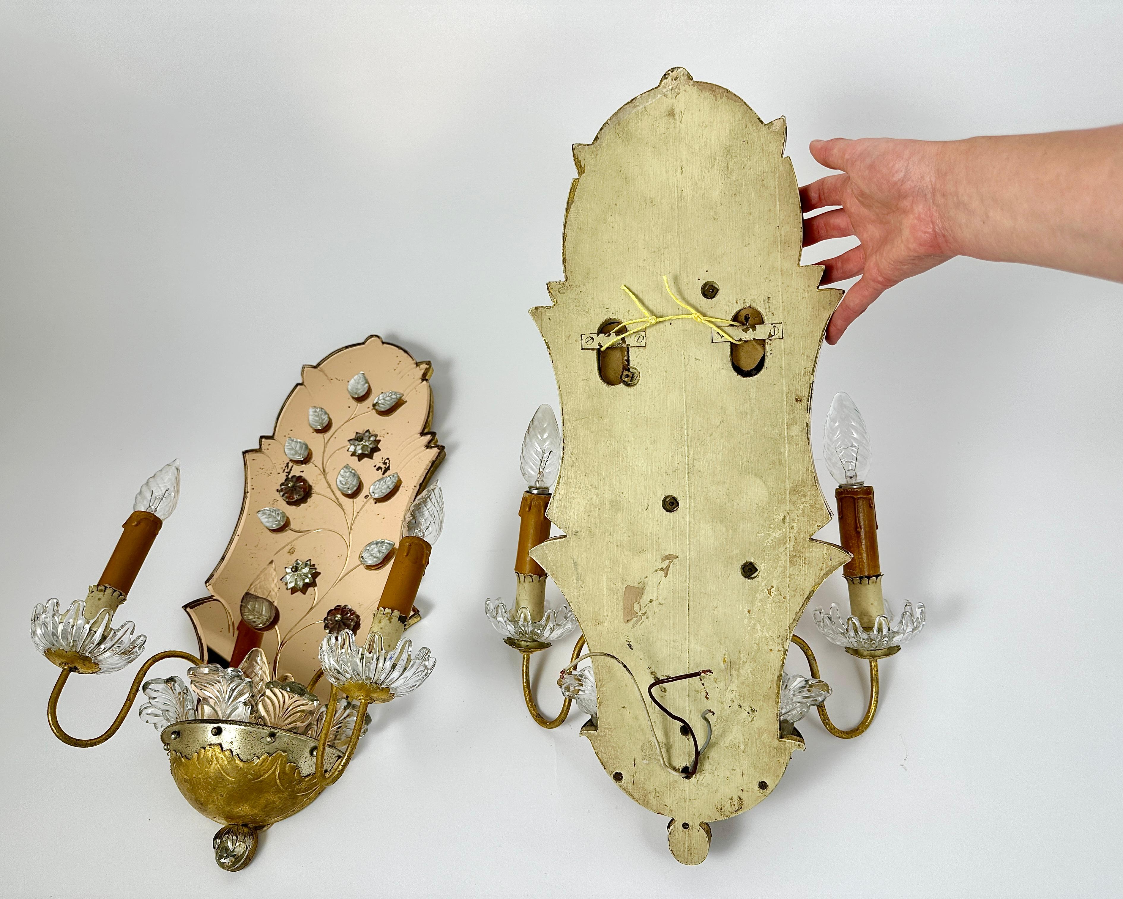 Set of two highly decorative and beautiful Mid-Century Modern crystal, gilt metal and mirror sconces or wall lamps decorated with leaves and stars.

Manufactured in Italy, 1950s.

Pair of wall lights with three light points on each.

Vintage