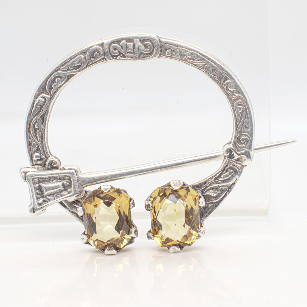 A fine vintage Scottish Brooch or Pin.

A so-called Penannular brooch traditionally used as a closure for cloaks or plaids.

Comprised of a cast silver C shaped body terminating with 2 prong-set faceted citrine gemstones and mounted with a cast