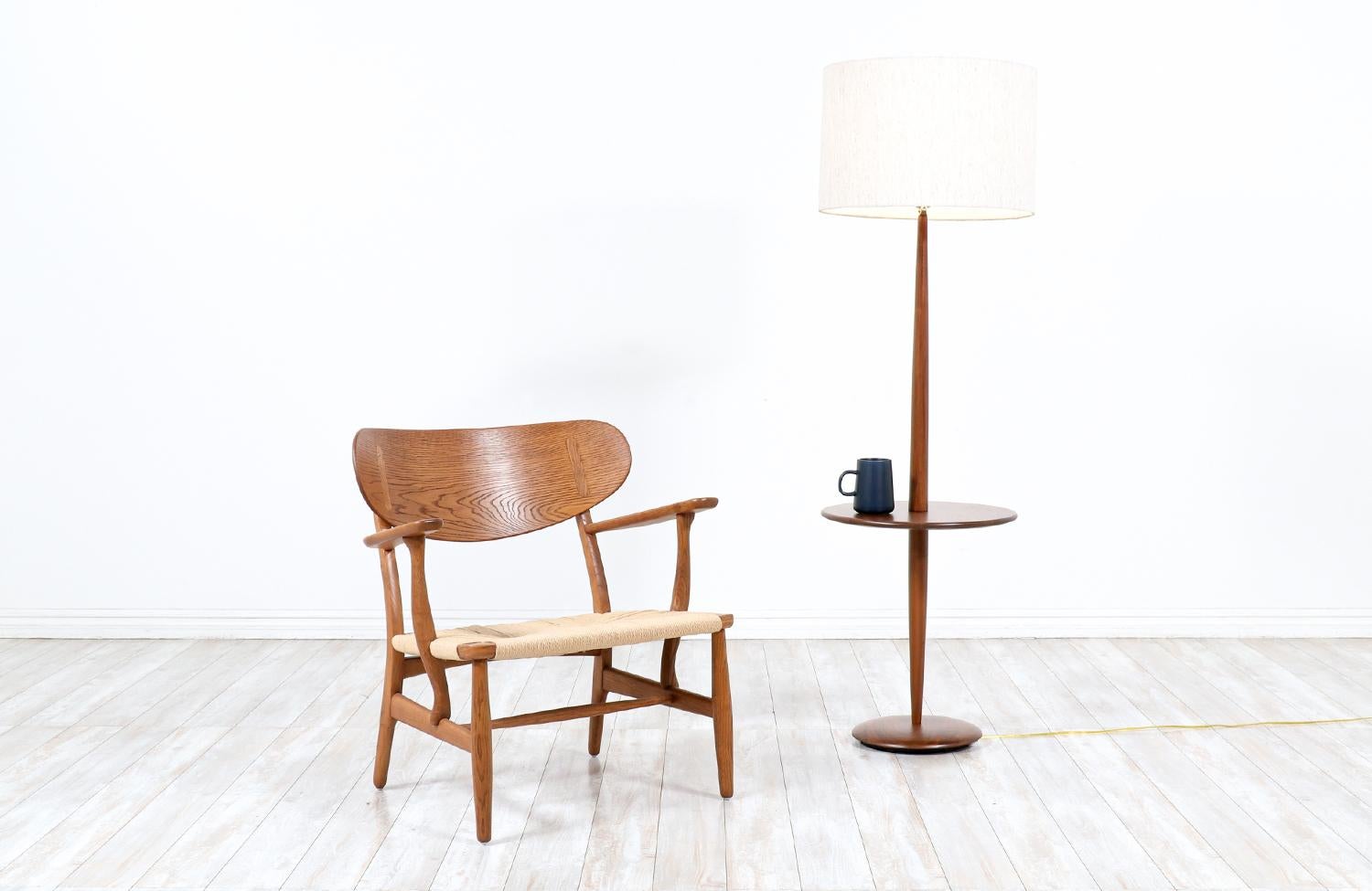 Floor Lamp manufactured by Laurel Lamp Co. in the United States circa 1960’s. This beautiful Mid-Century Modern lamp features a tall walnut wood body that supports a table. This lamp is newly rewired with new brass hardware and a custom linen