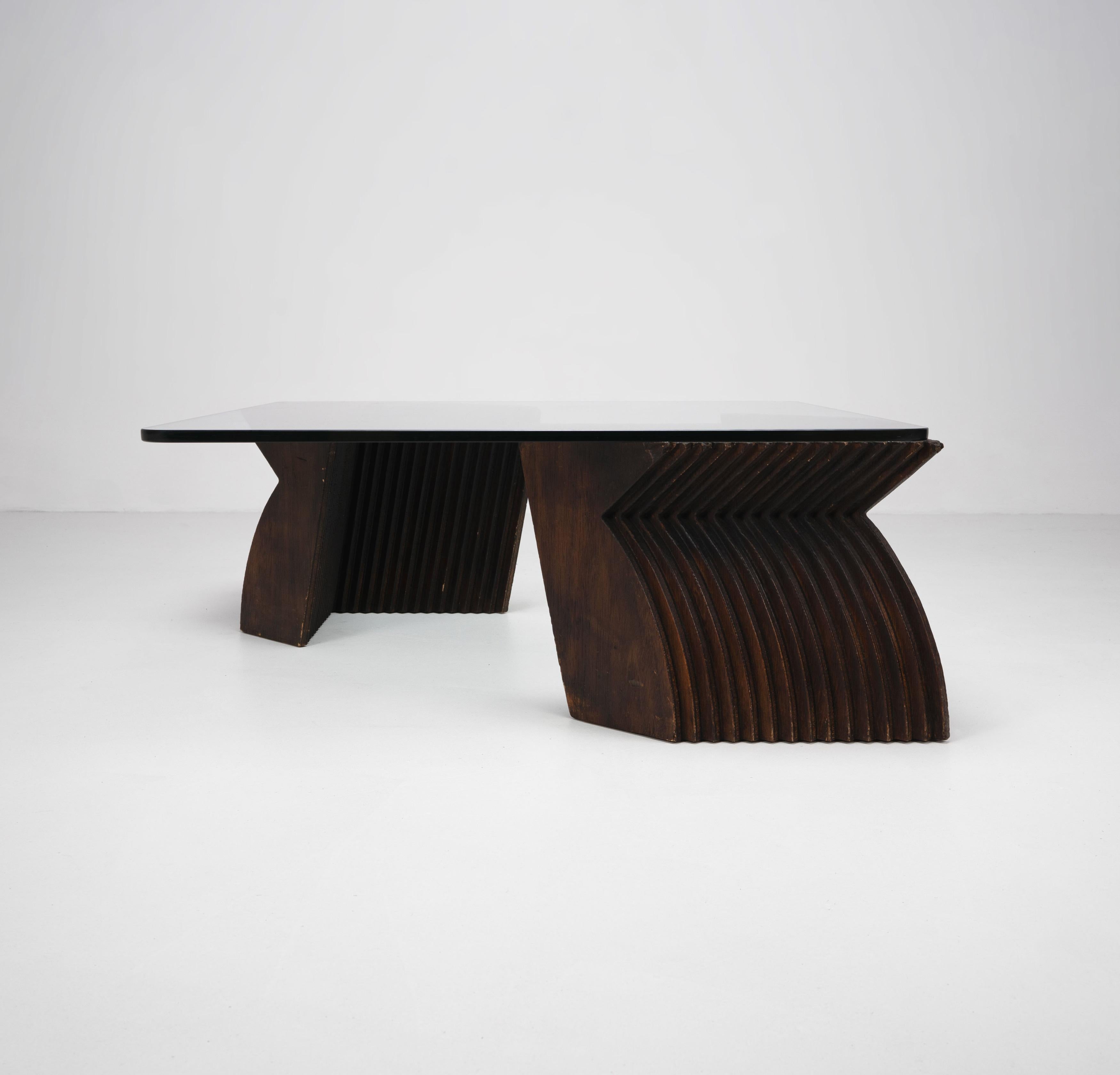 A late 20th Century coffee table composed from two sculptural base elements formed from layered, stained plywood pieces creating Futurist style forms. 

Dimensions (cm, approx):
Height: 37
Width: 89.5
Depth: 89.5

Condition: Fair condition for year